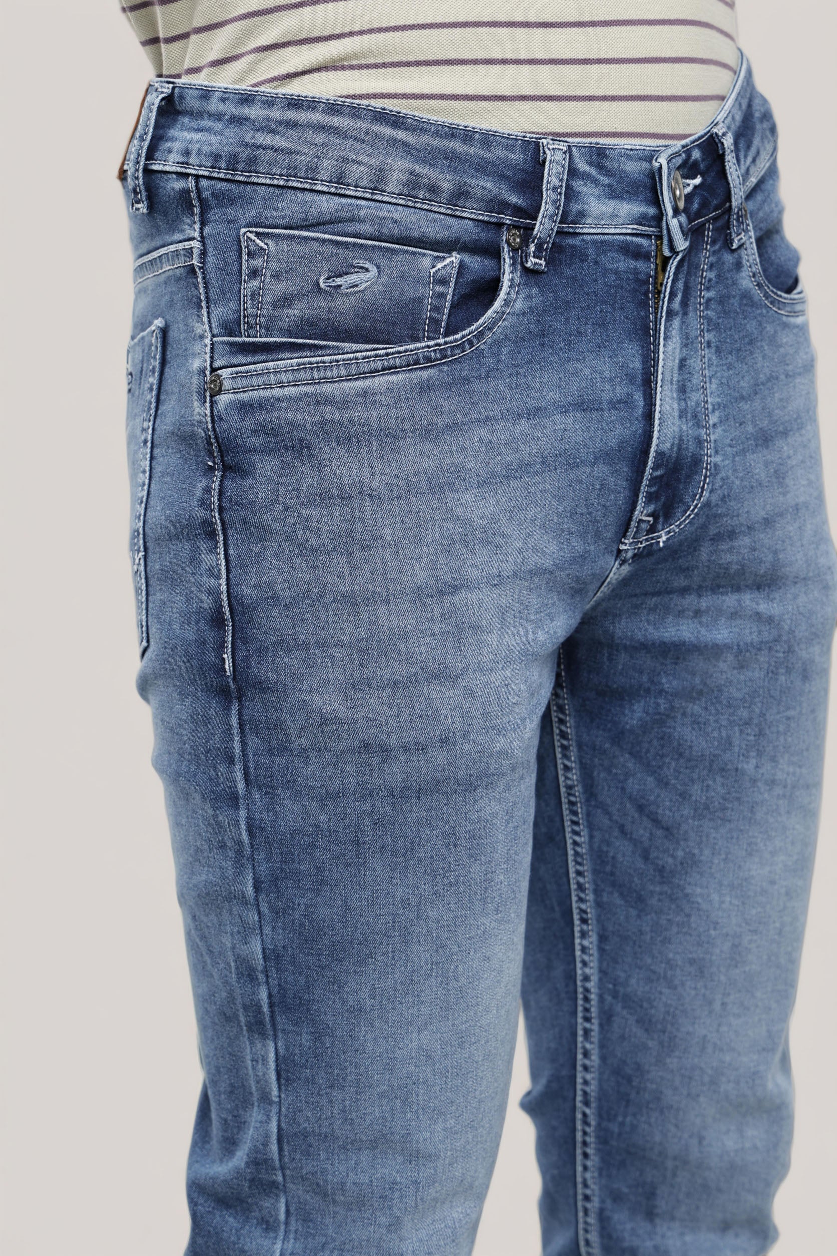 Blue jeans worn by a person on a plain background