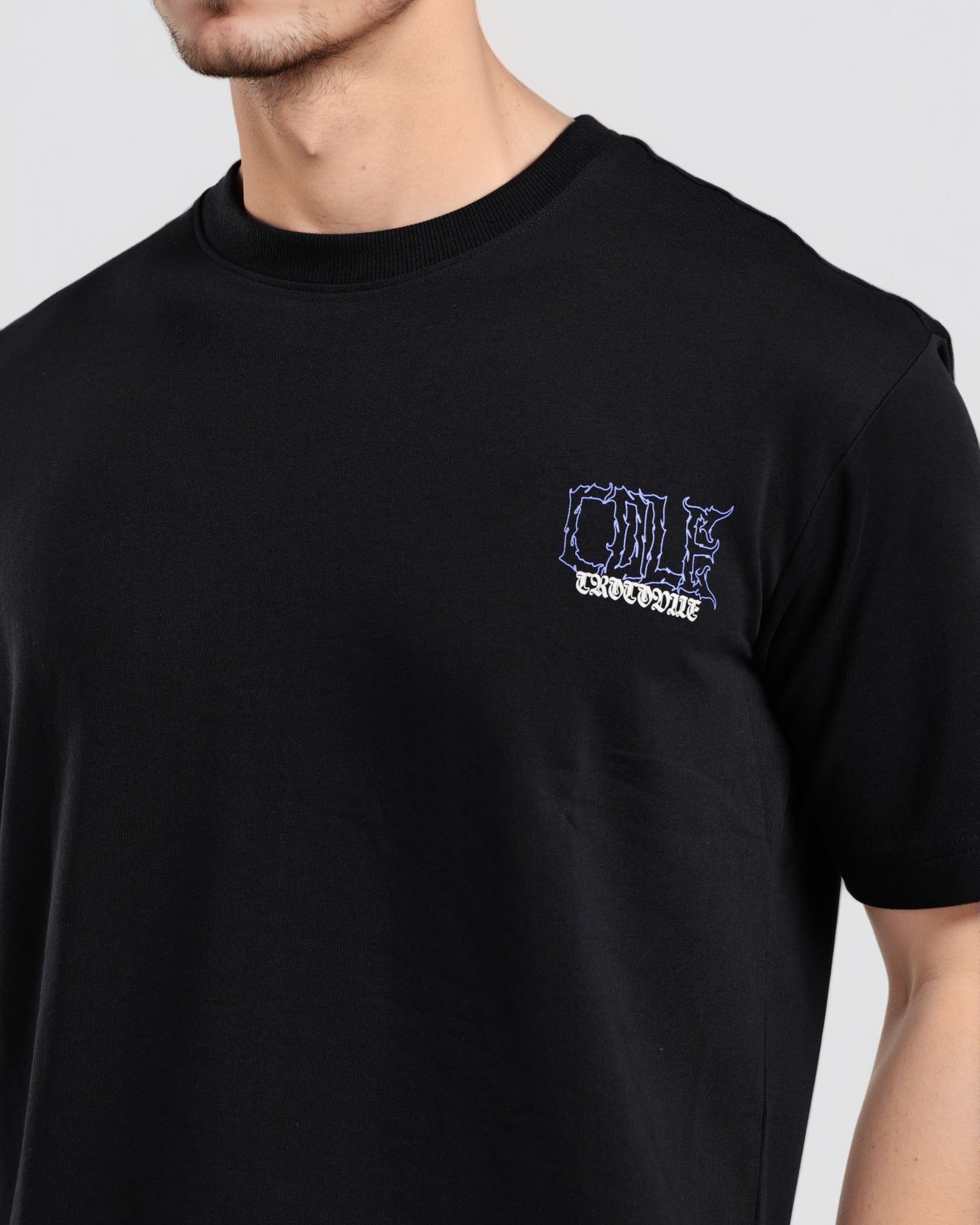 Black t-shirt with a small logo on the chest worn by a person against a plain background