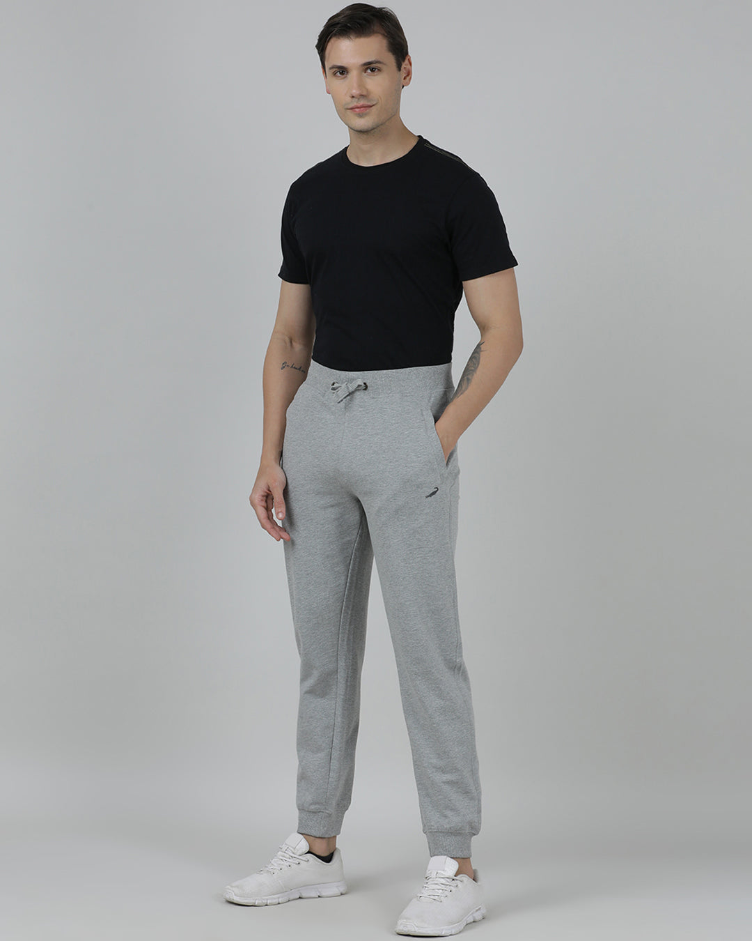 Man wearing a black t-shirt and gray sweatpants on a plain background