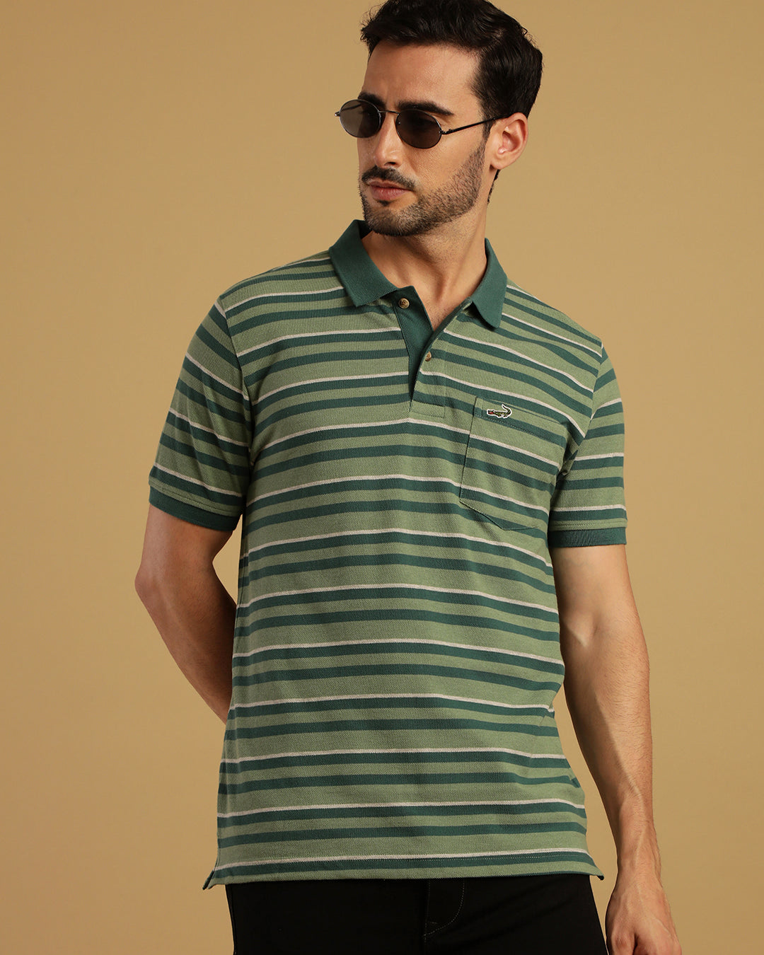 Man wearing a green green striped polo t shirt on a light gray background
