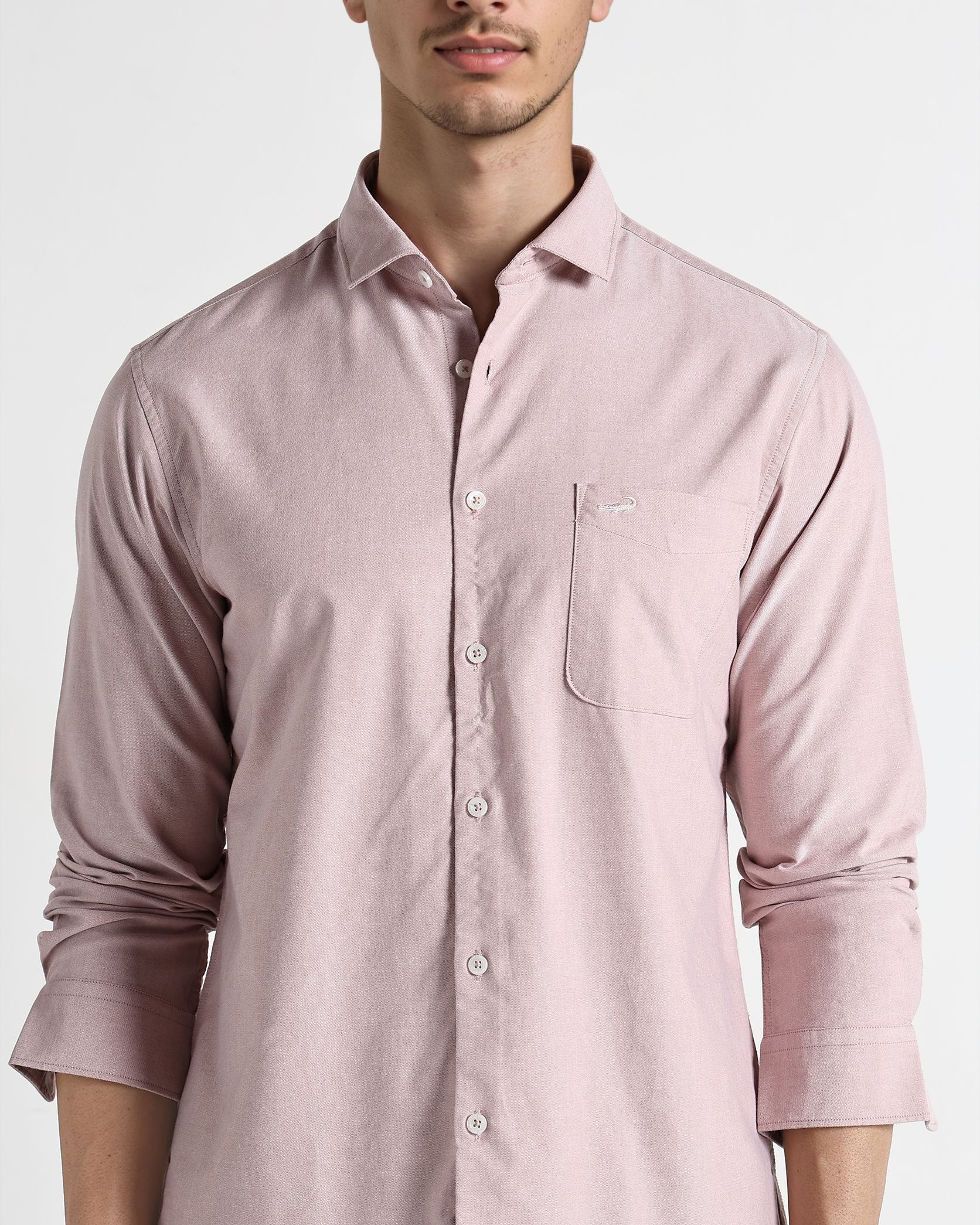 Man wearing a light pink shirt against a white background