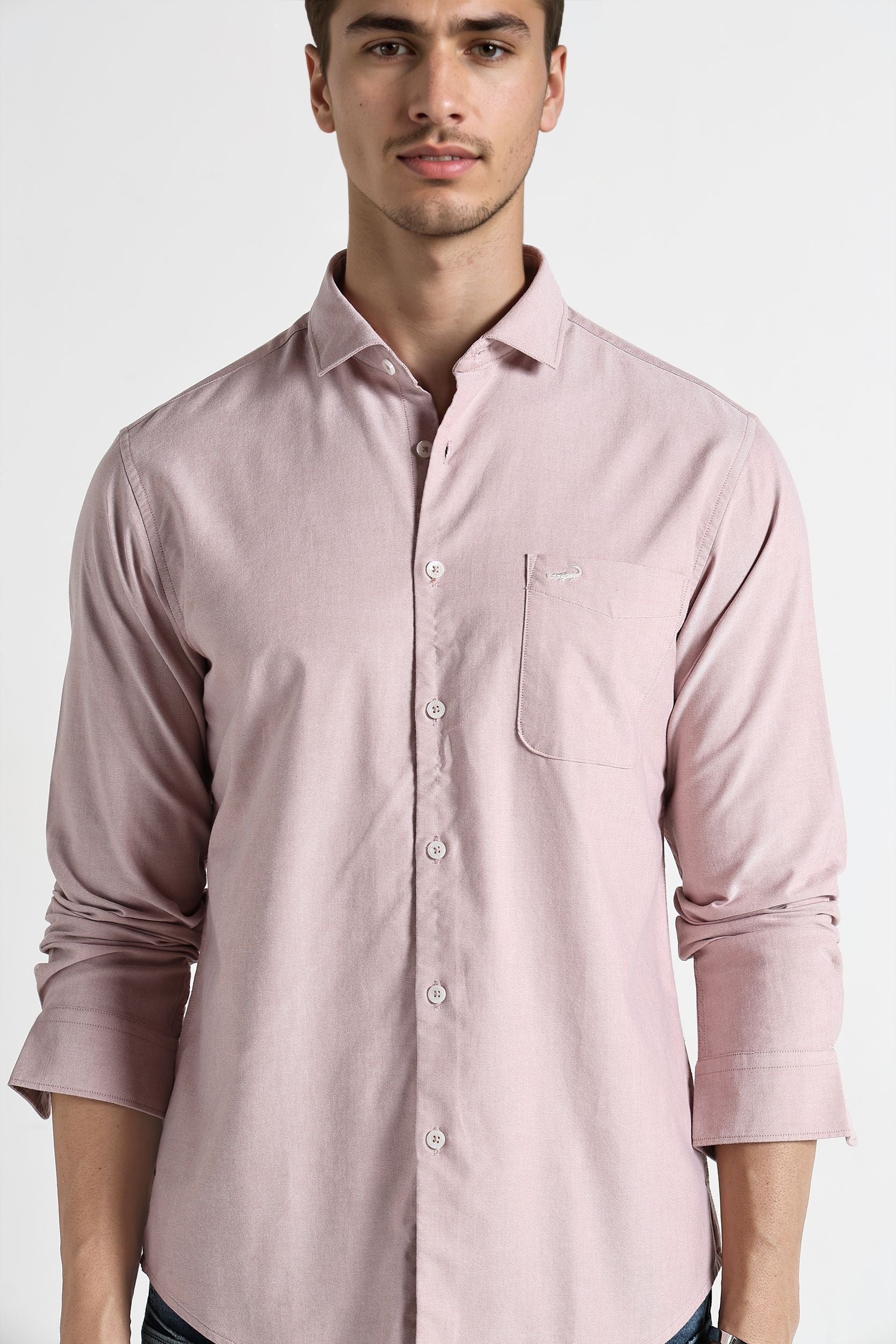 Man wearing a light pink shirt against a white background