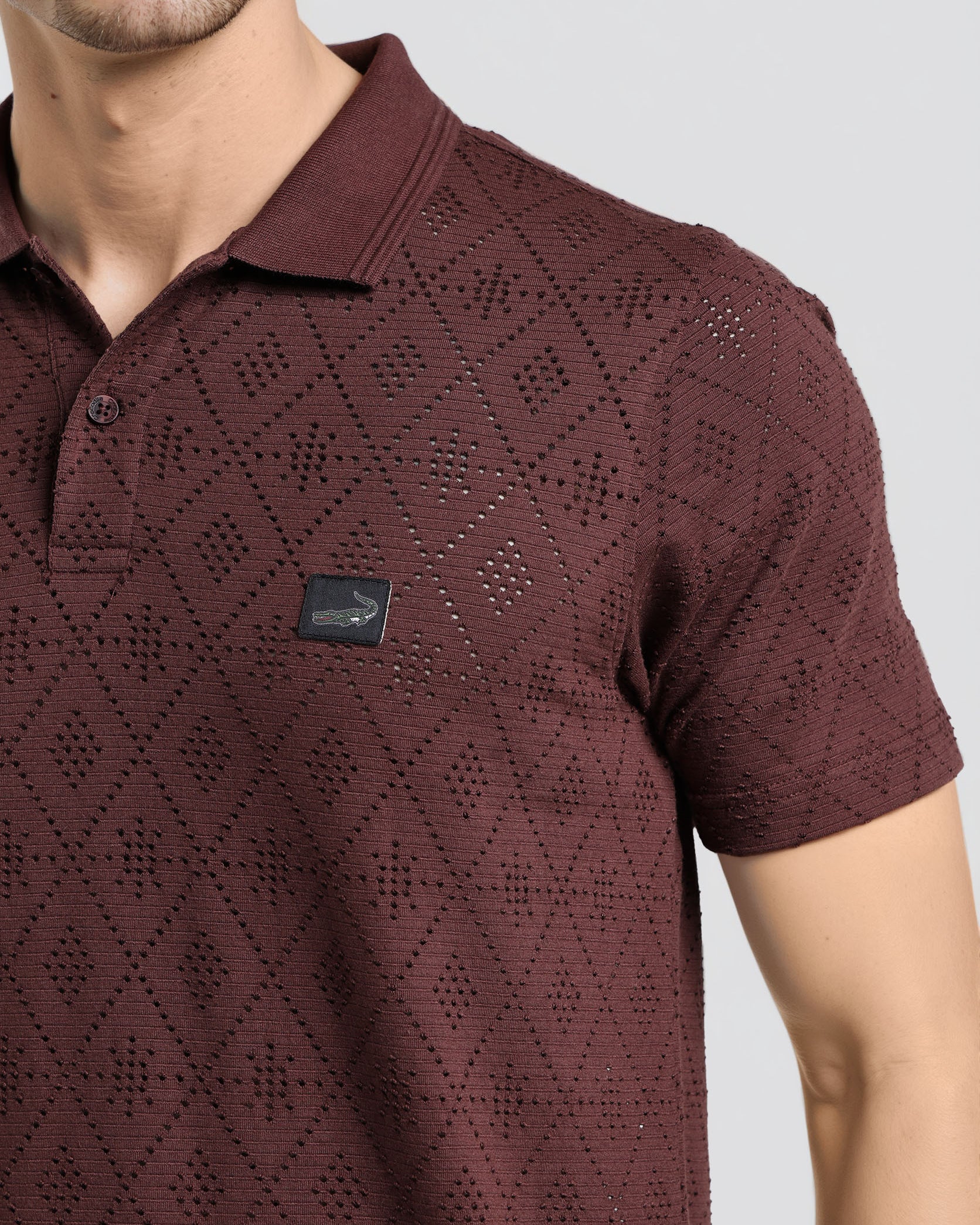 Maroon patterned polo shirt worn by a person on a light gray background