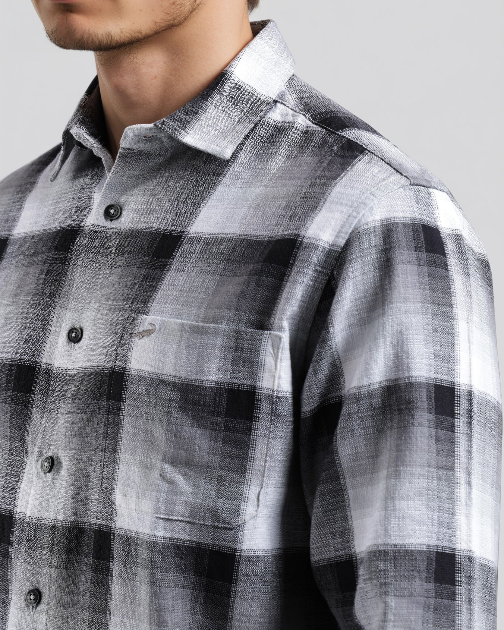 Man wearing a gray and white plaid shirt against a plain background