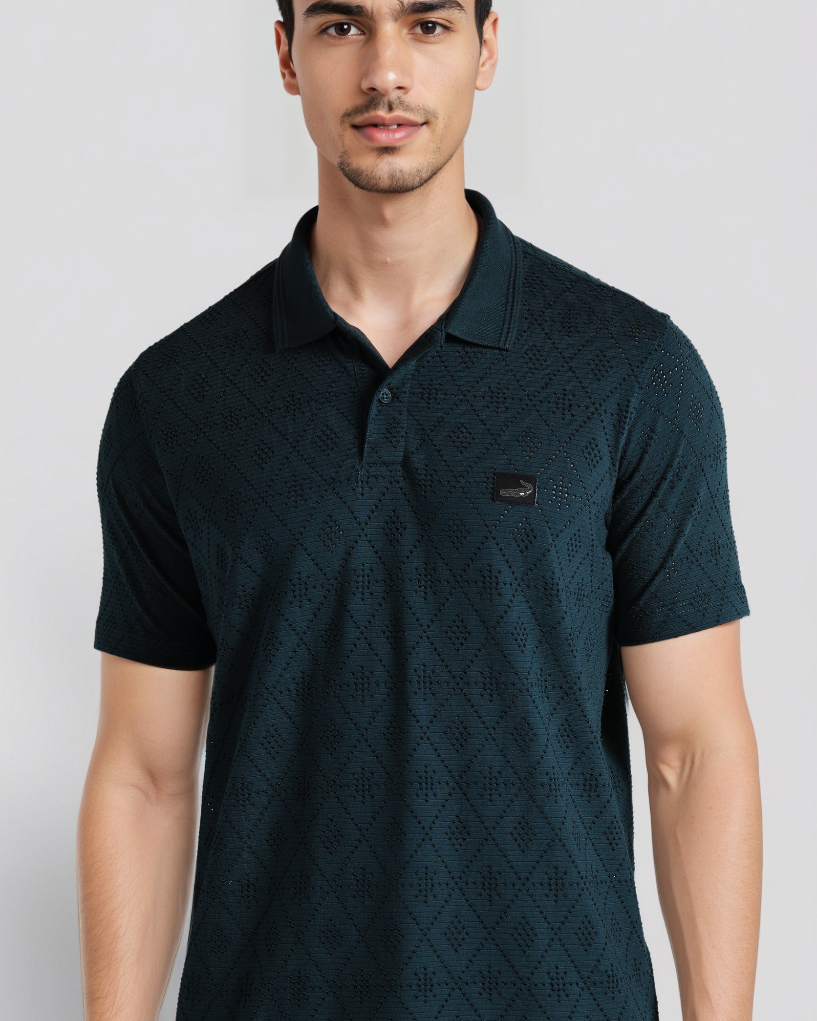 Man wearing a dark green patterned polo shirt on a light gray background