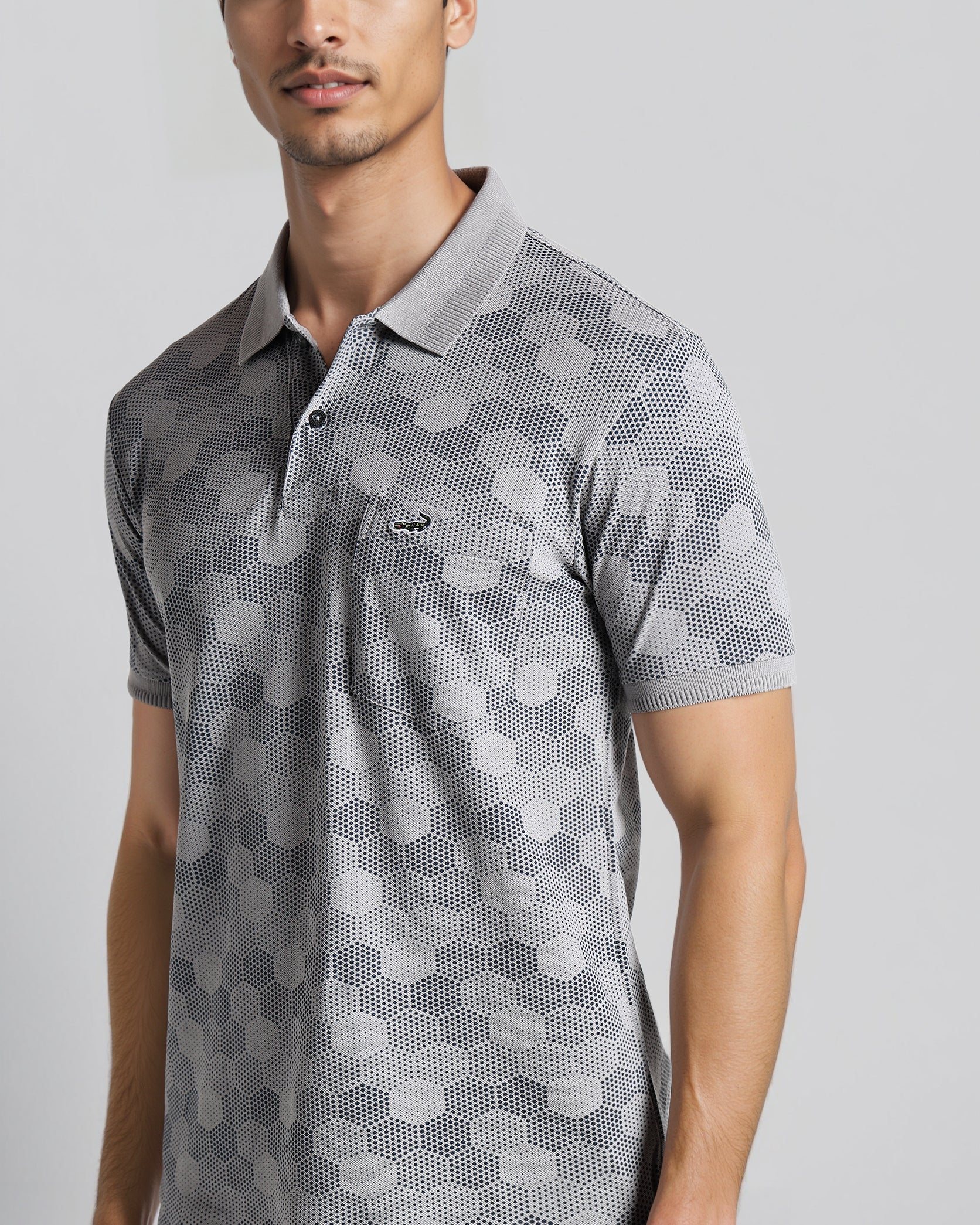 Man wearing a gray patterned polo shirt on a light gray background