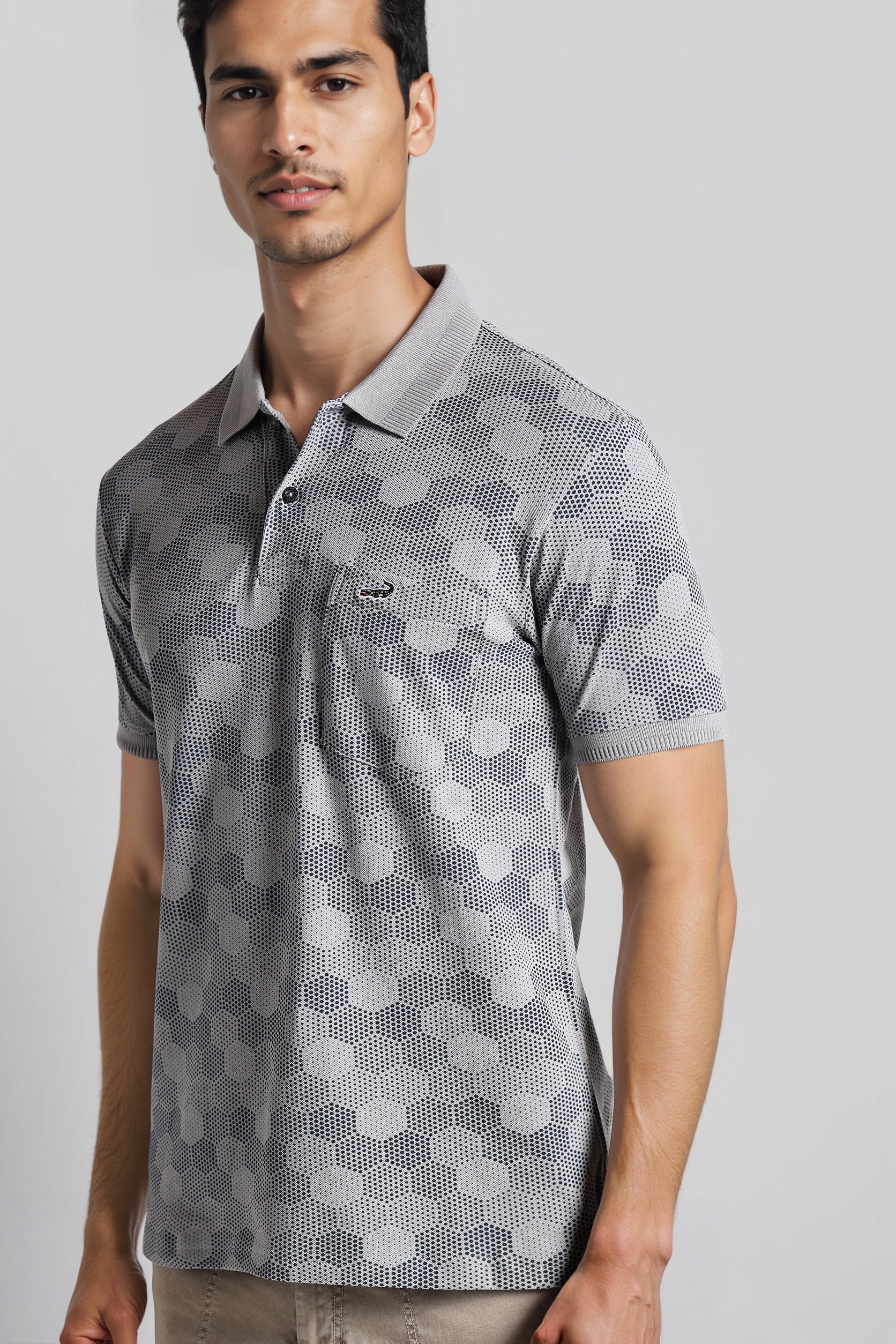 Man wearing a gray patterned polo shirt on a light gray background