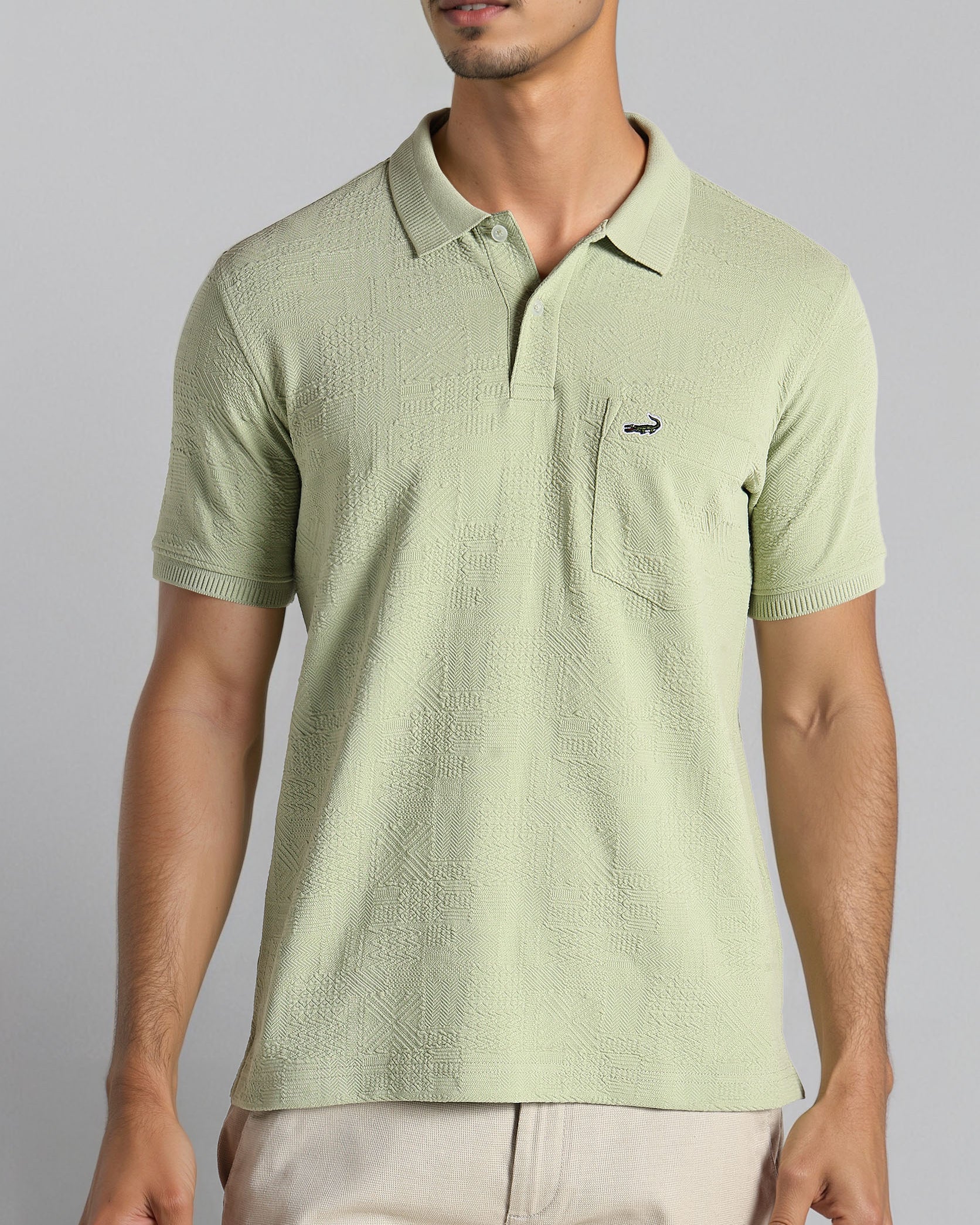 Man wearing a light green polo shirt with a small logo on a gray background