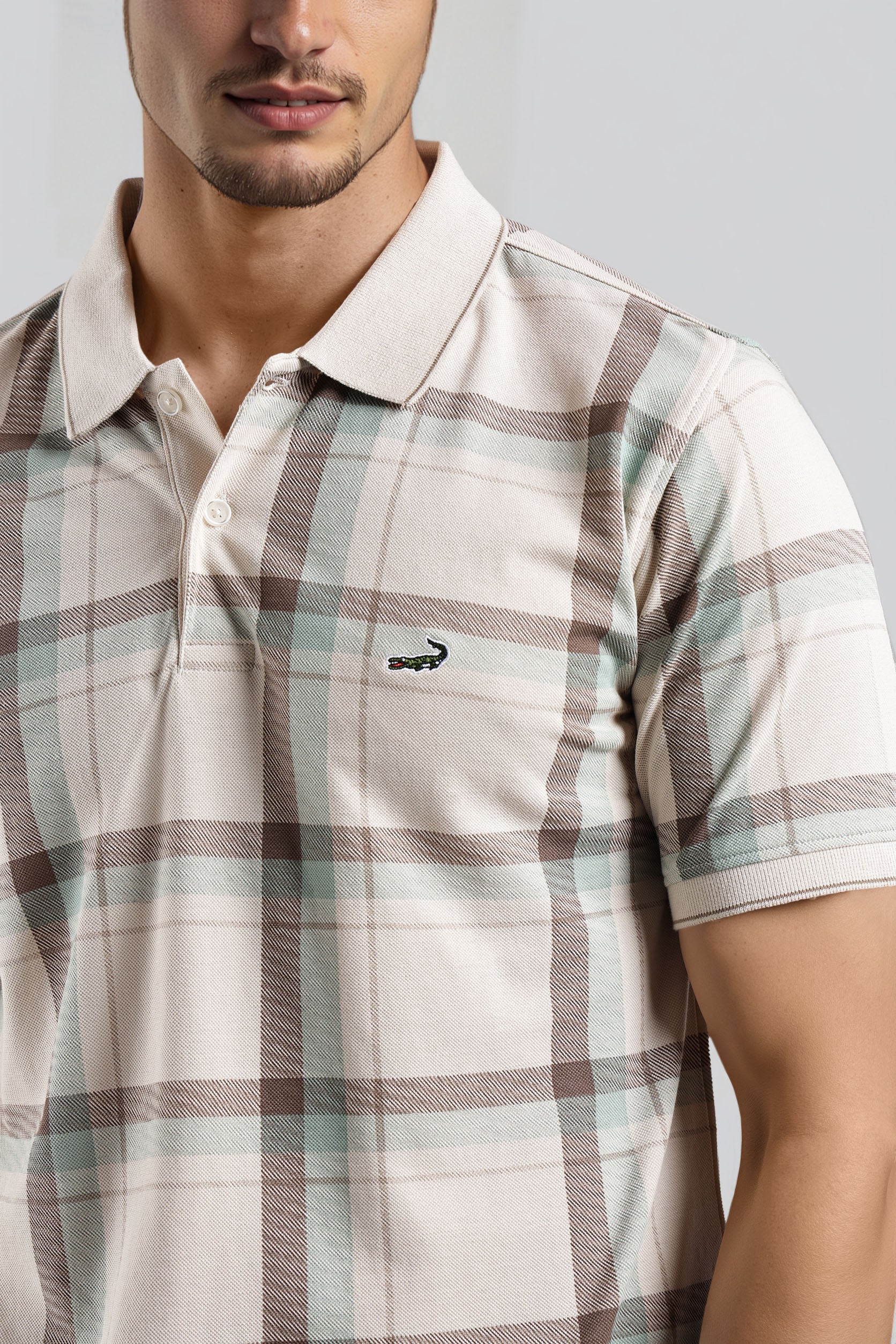 Man wearing a plaid shirt with a brand logo on a gray background