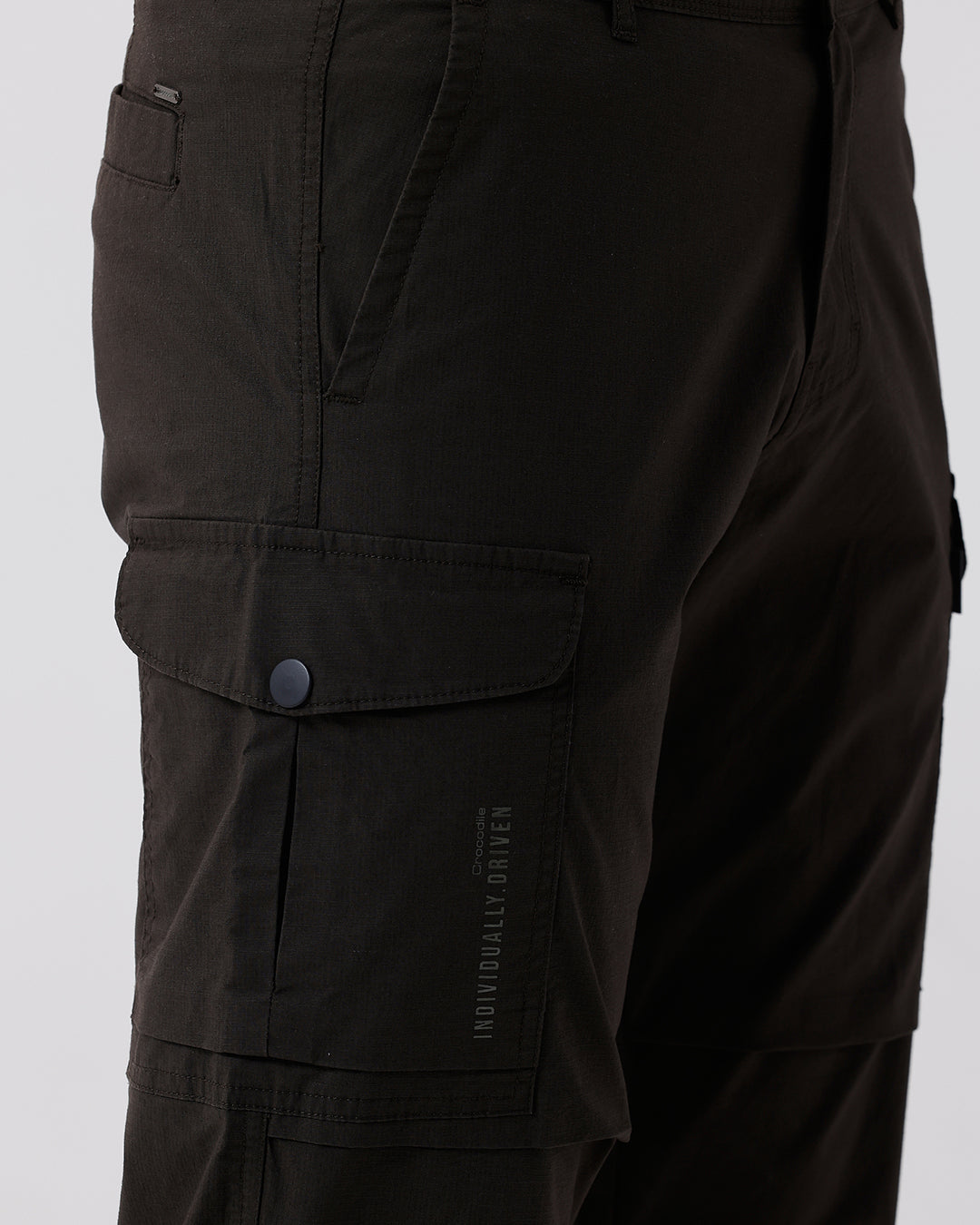 Man wearing a grey utility trekflex cargo pant in dark grey on a light gray background