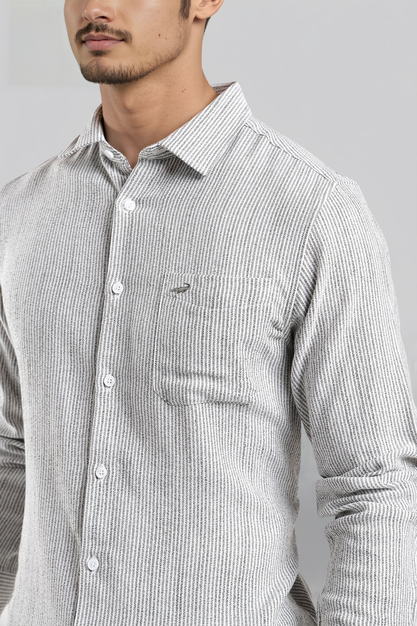 Man wearing a gray striped shirt with a brand logo on a gray background