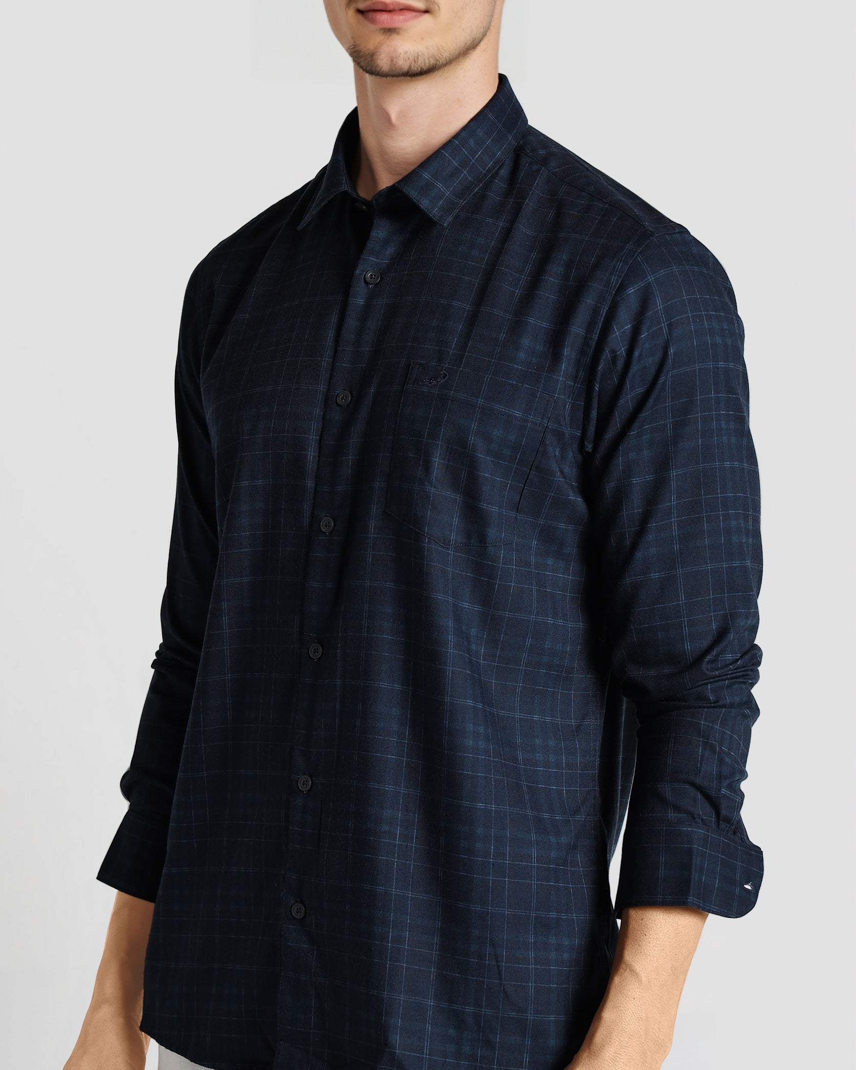 Man wearing a dark blue checkered shirt on a light gray background