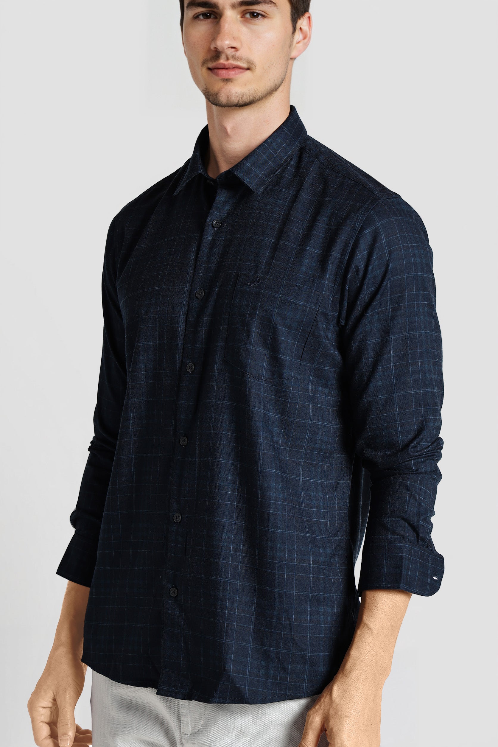 Man wearing a dark blue checkered shirt on a light gray background