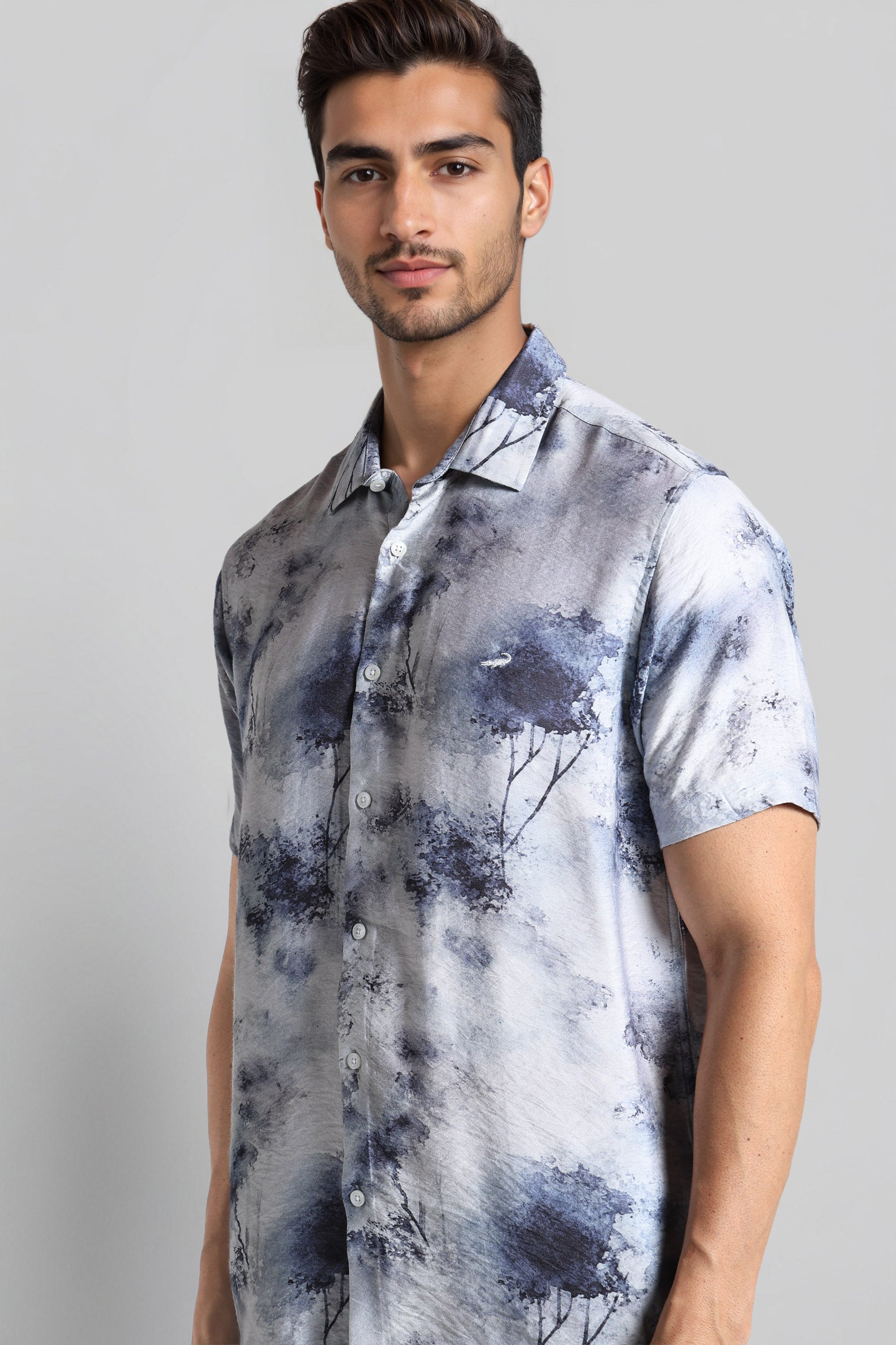 Man wearing a short-sleeve shirt with abstract design on a gray background