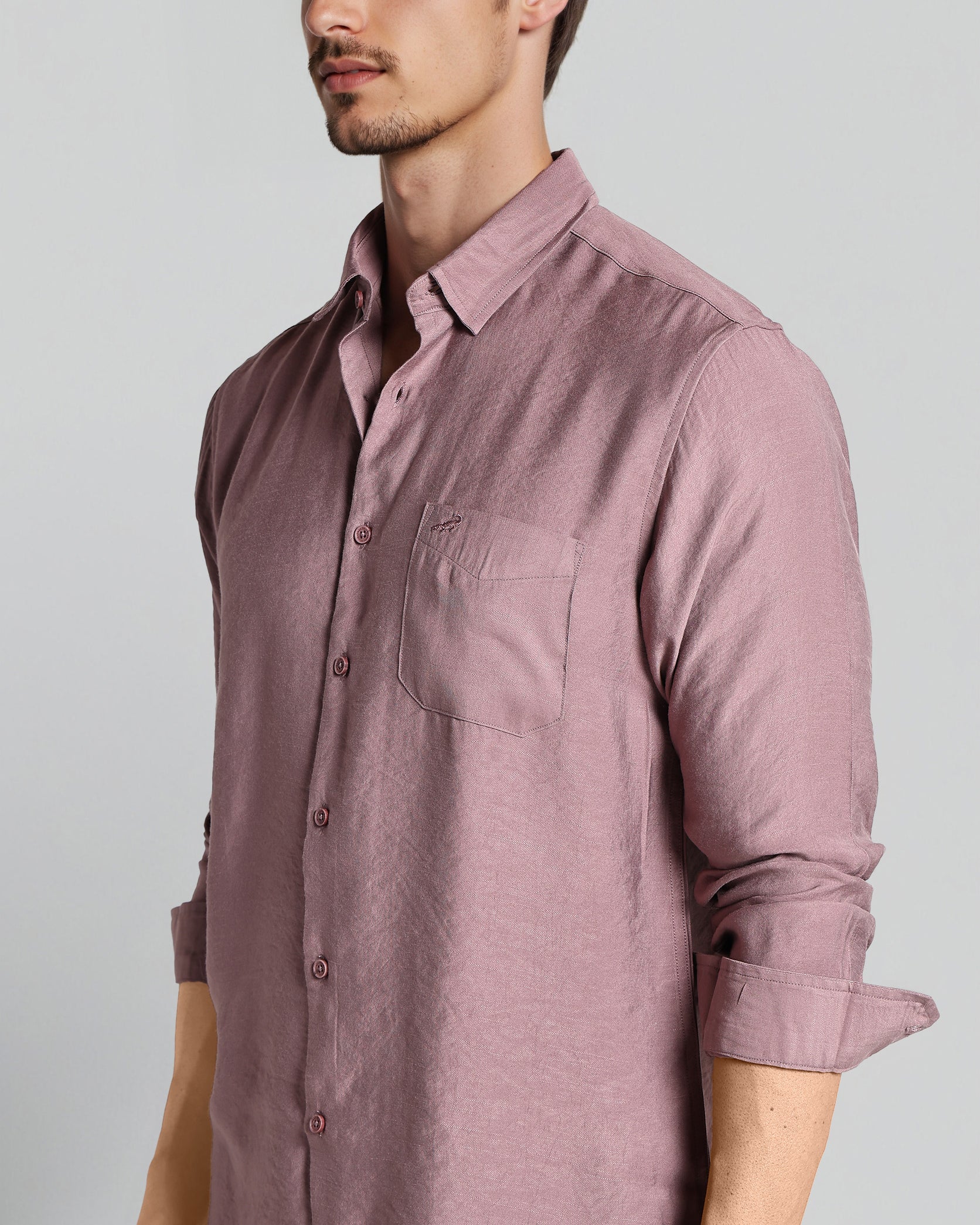 Man wearing a mauve button-up shirt against a gray background
