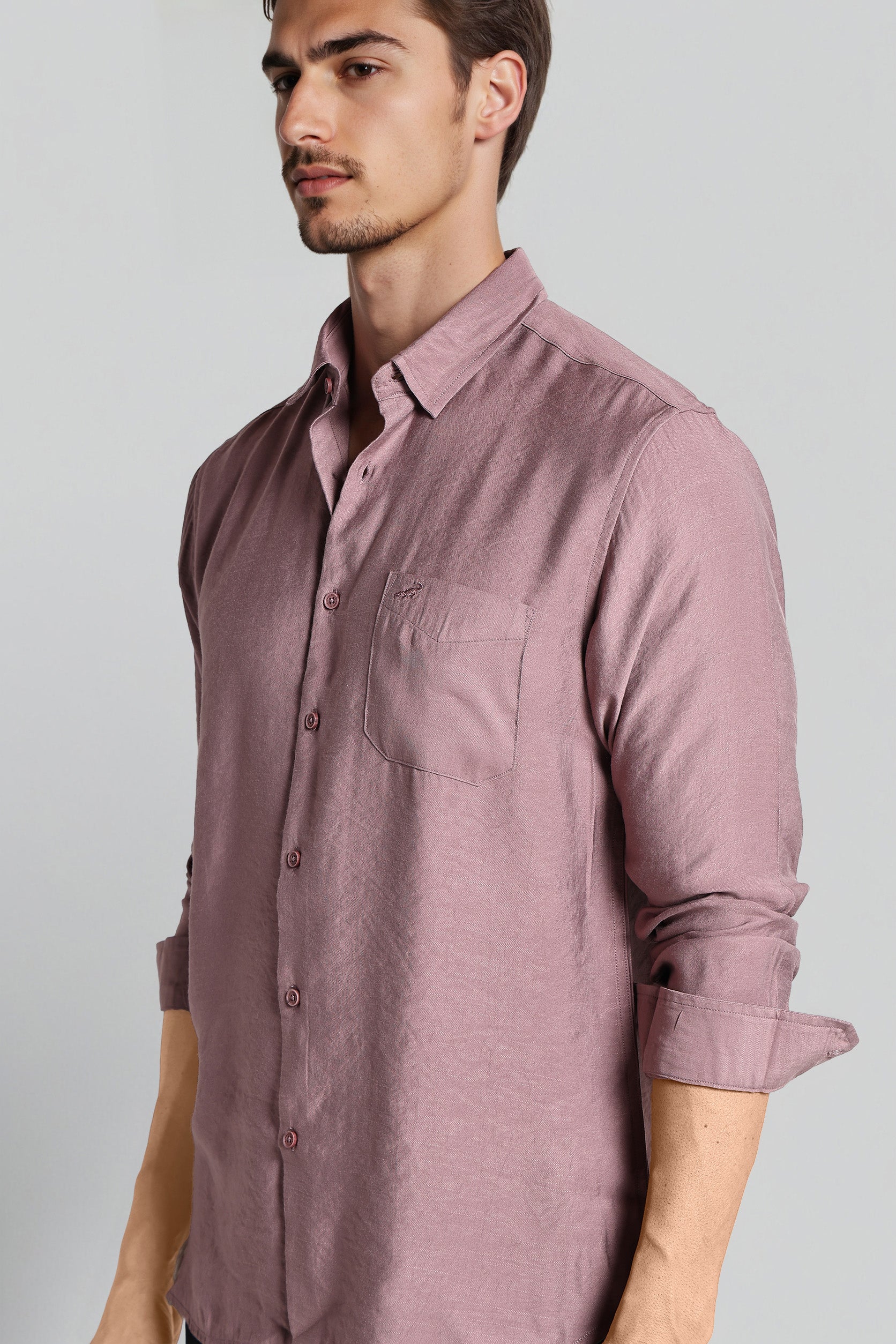 Man wearing a mauve button-up shirt against a gray background