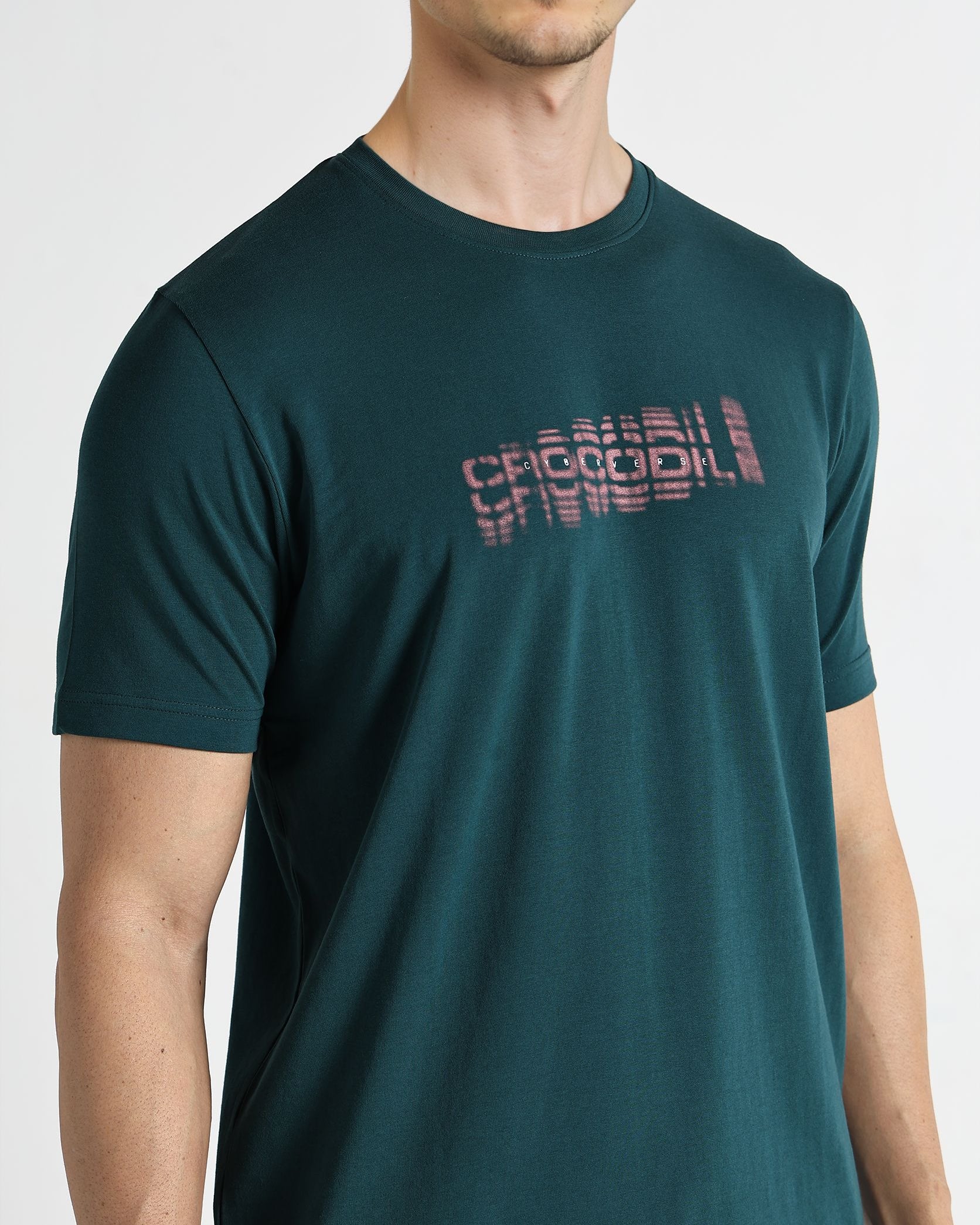 Man wearing a dark green t-shirt with a logo on a white background