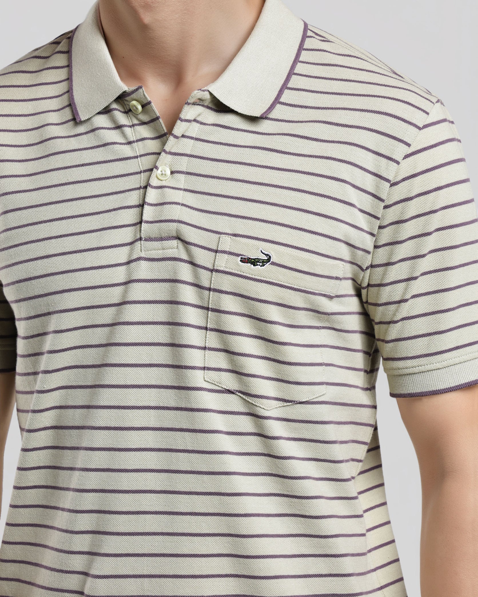 Man wearing a striped polo shirt with a brand logo on a light gray background