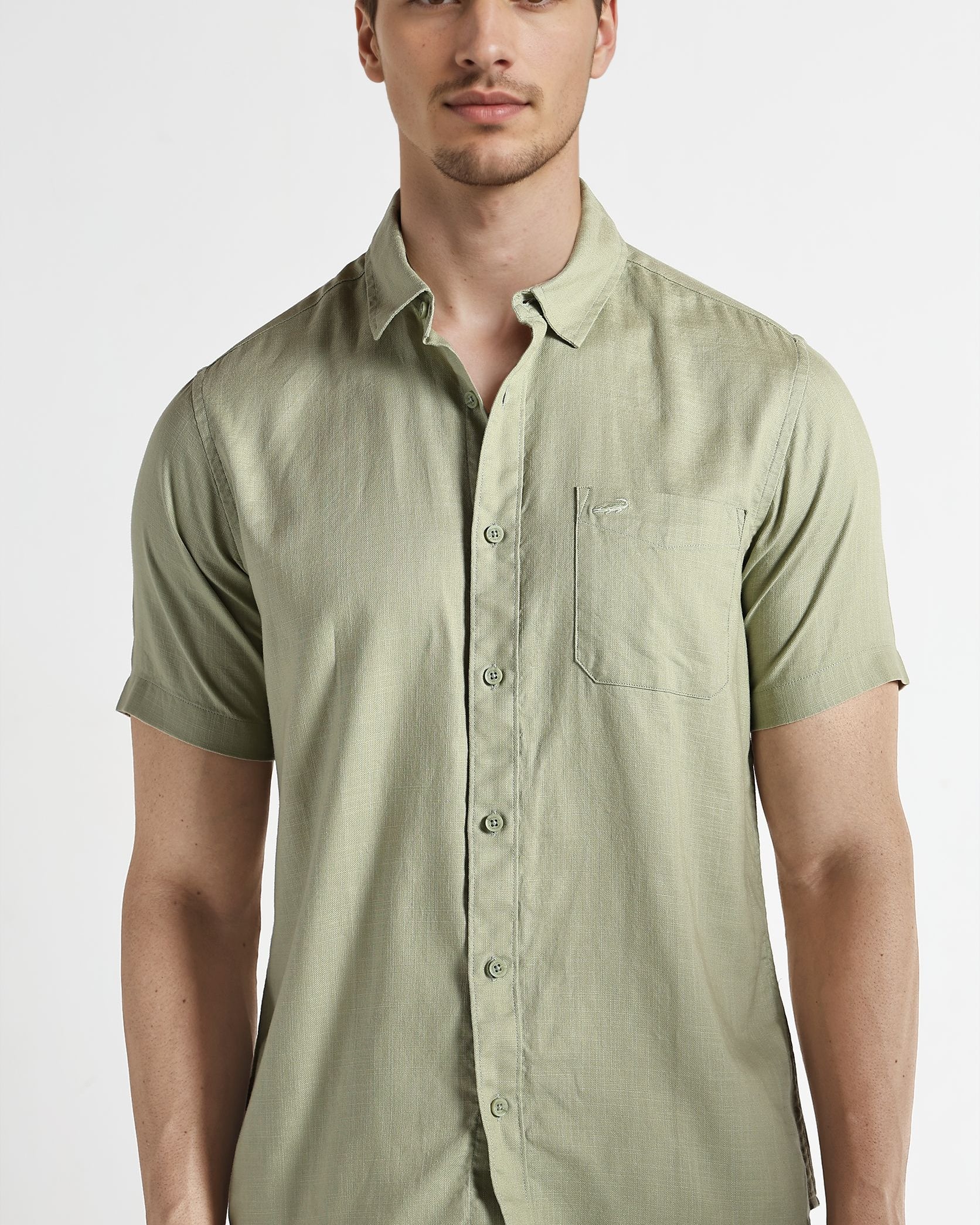 Man wearing a light green short-sleeve shirt on a white background