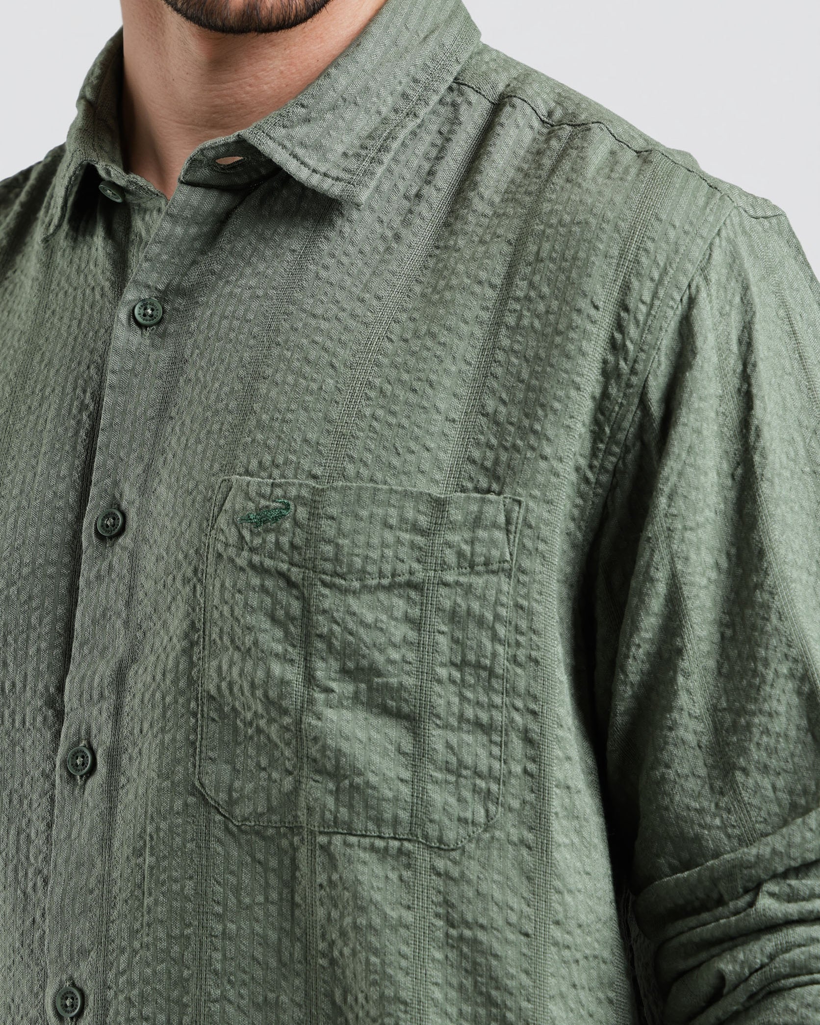 Green textured shirt worn by a person on a light gray background