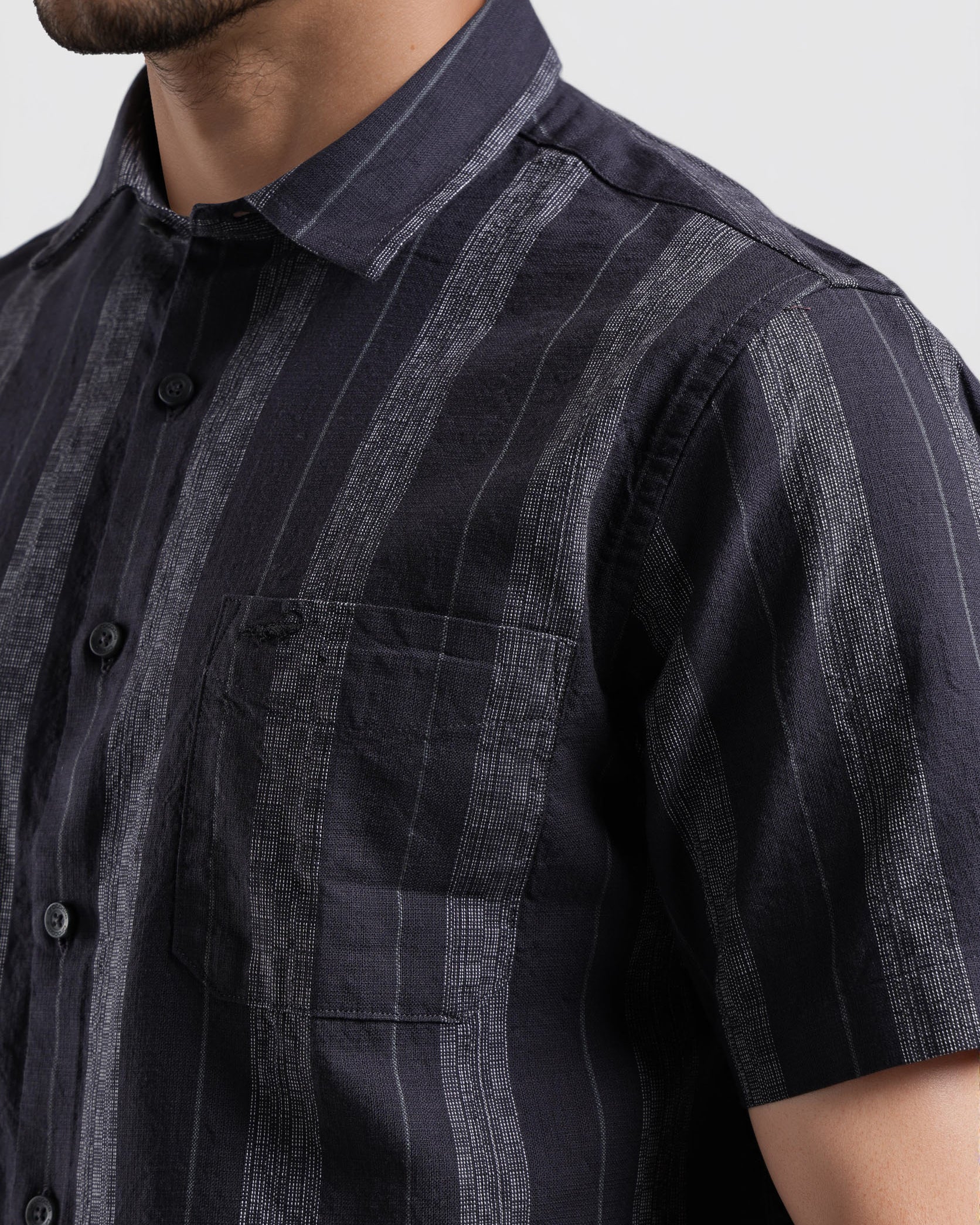 Man wearing a dark blue striped shirt against a white background