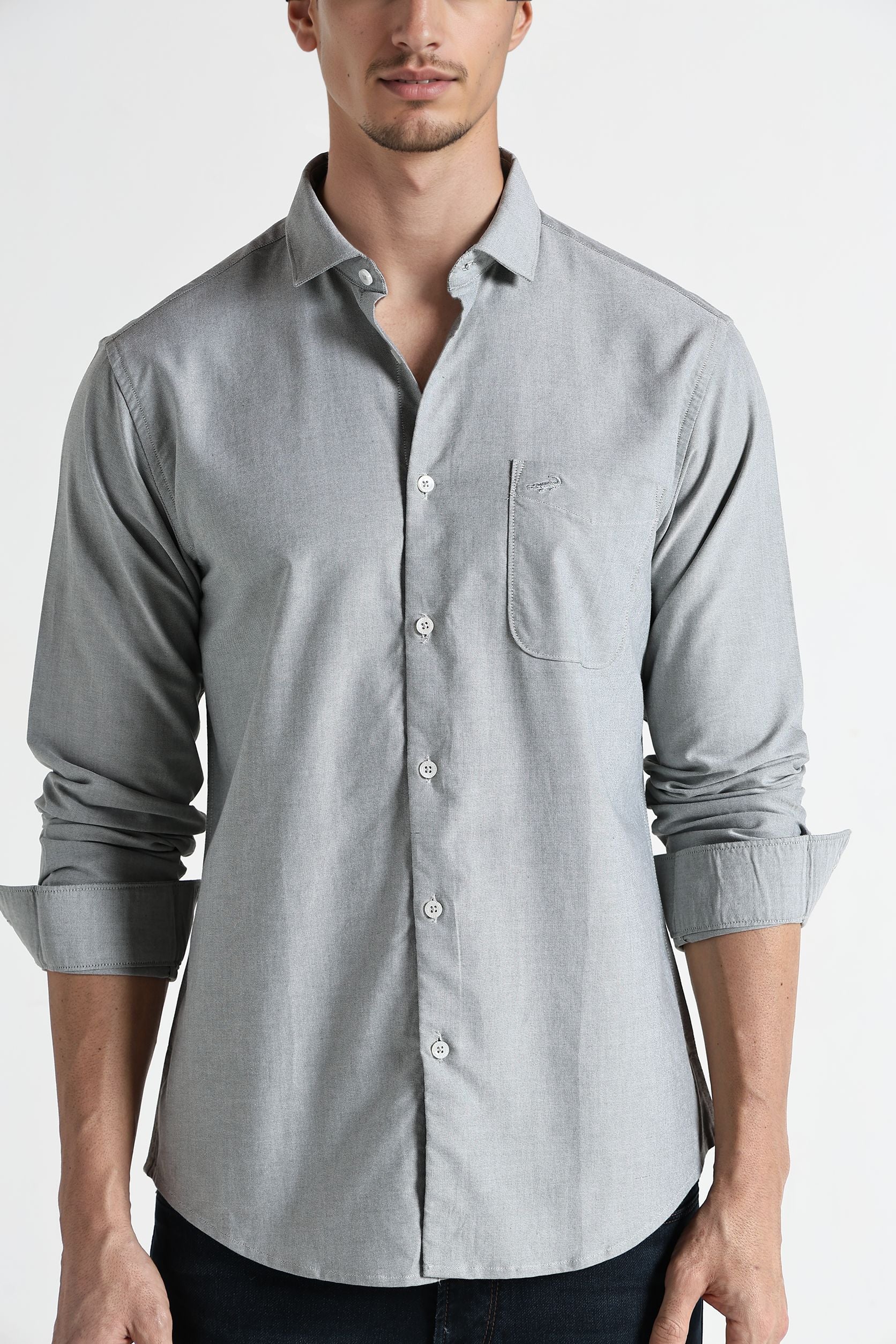 Man wearing a light gray button-up shirt with rolled-up sleeves on a white background