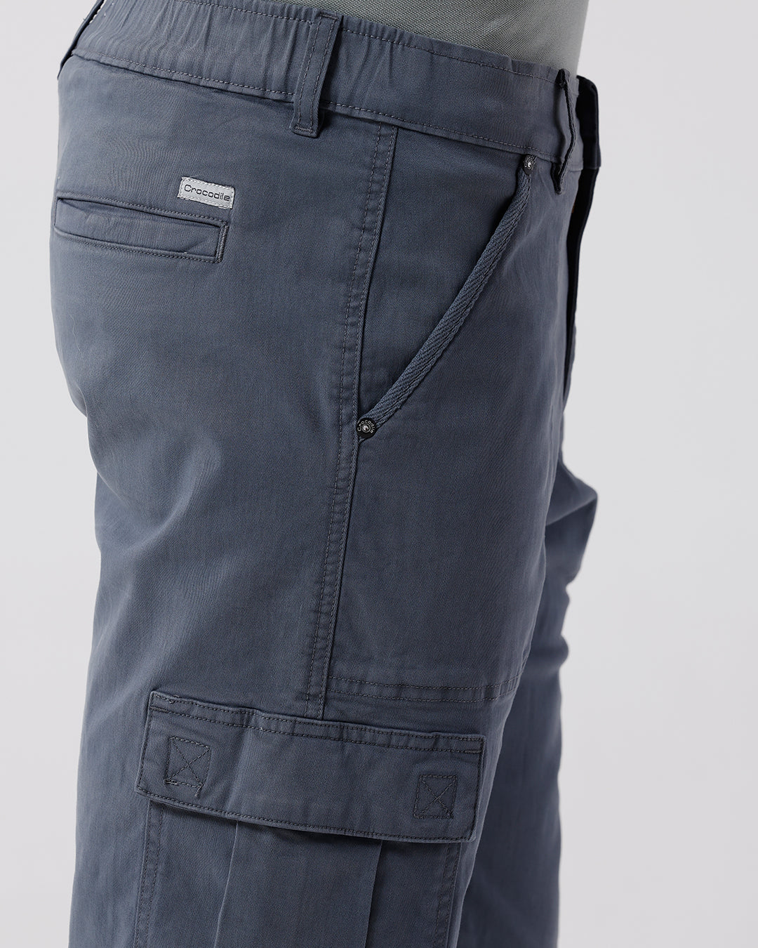 Man wearing a grey garment dyed cargo shorts in dark grey with casual styling on a gray background