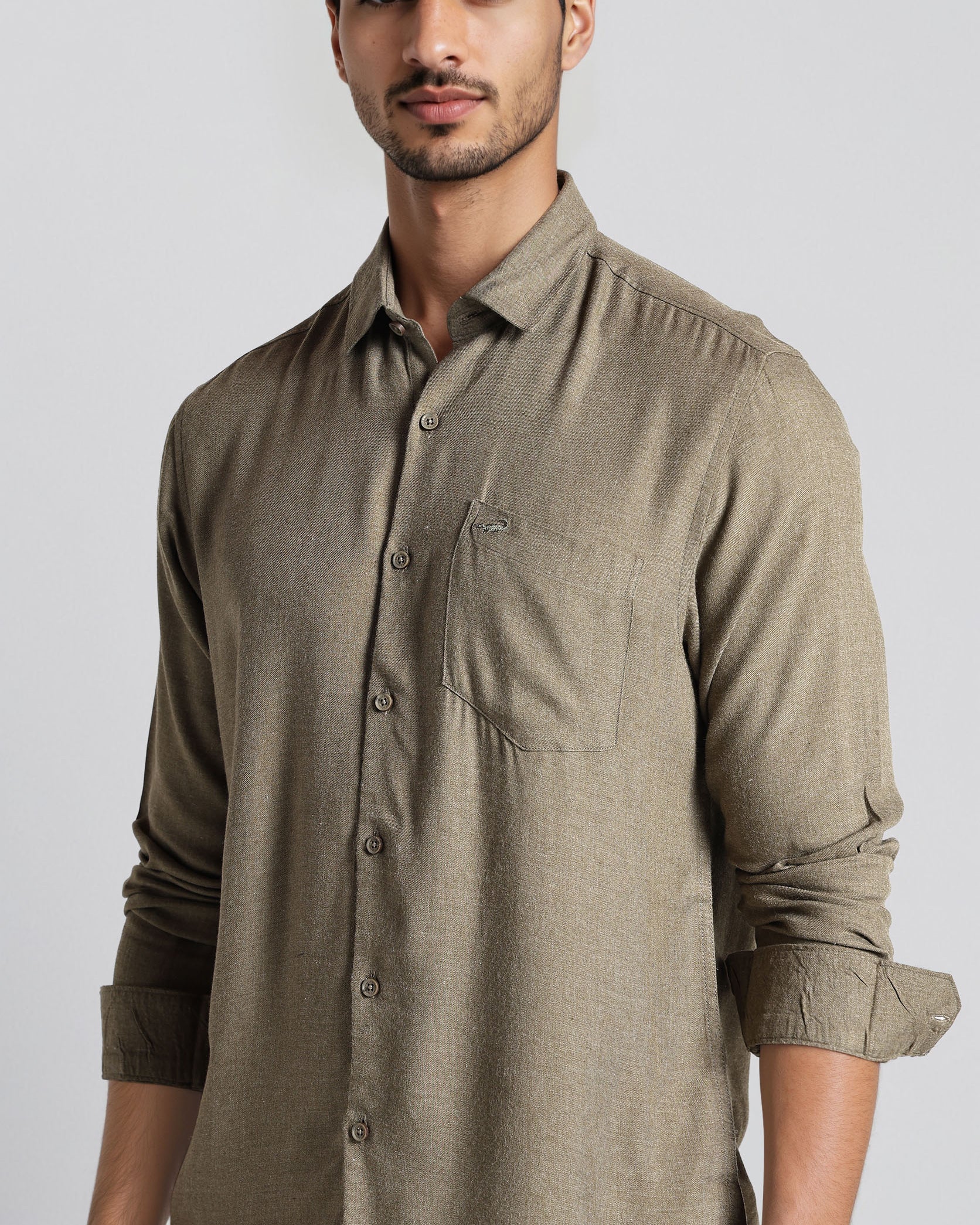 Man wearing a brown button-up shirt against a plain background