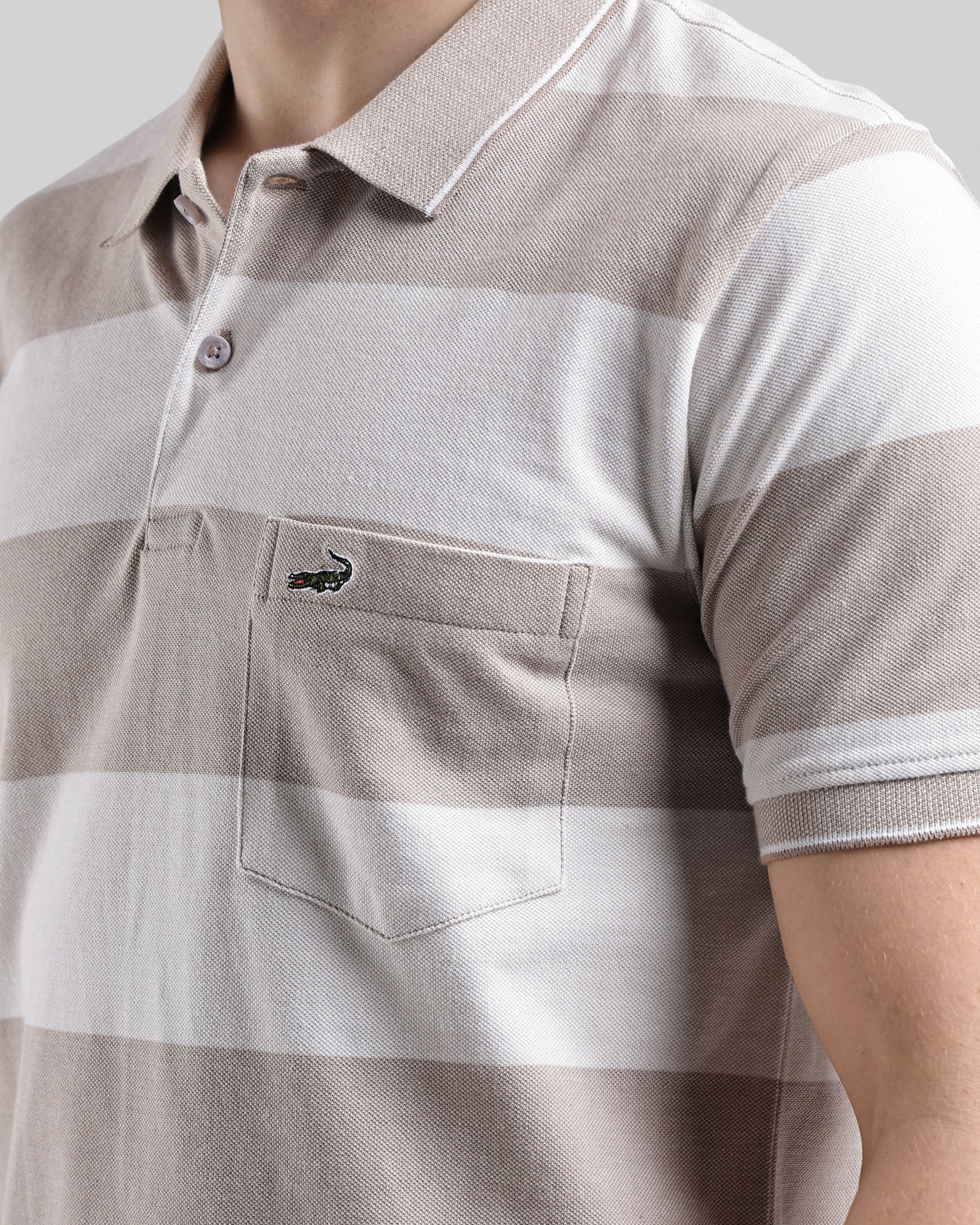 Close-up of a brown and white striped polo shirt with a brand logo on a light gray background