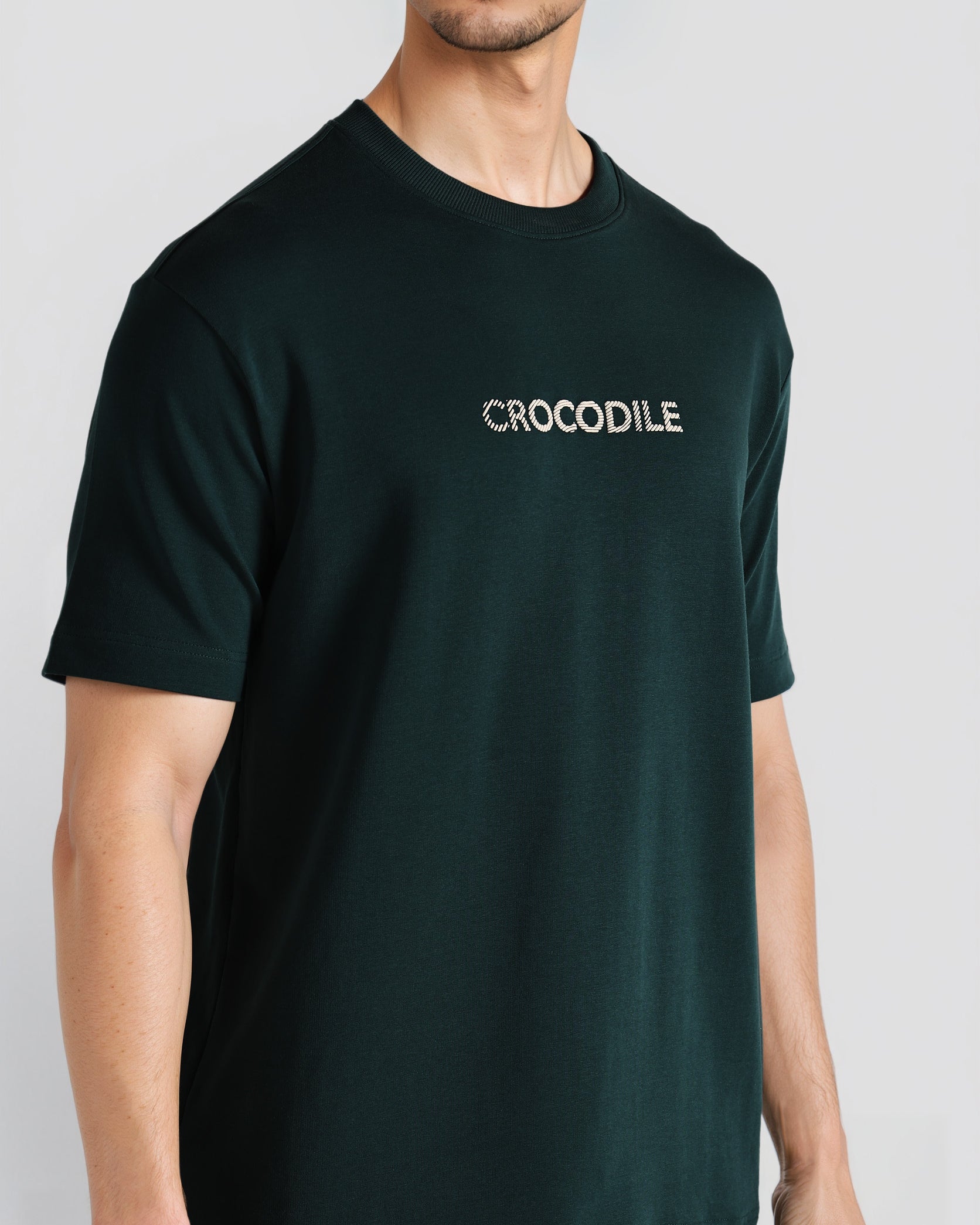 Person wearing a black t-shirt with 'CROCODILE' logo on a light gray background