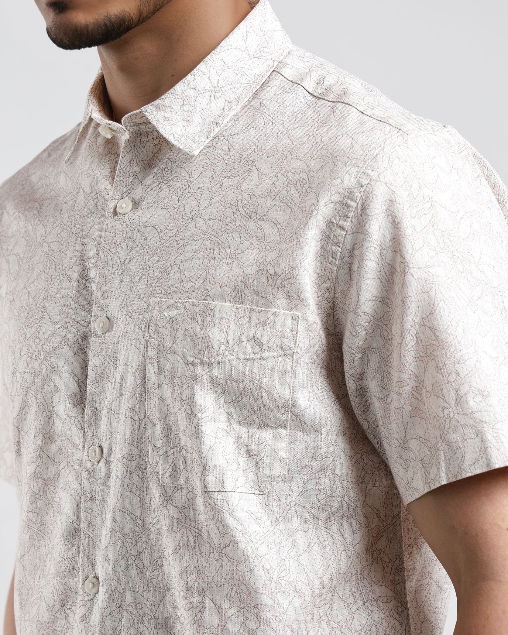 Man wearing a light-colored short-sleeve shirt against a plain background