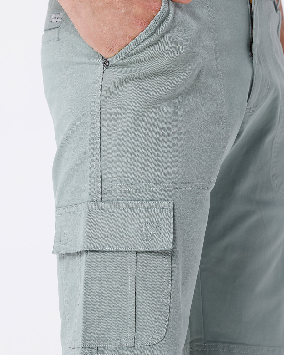 Man wearing a olive garment dyed cargo shorts in olive on a light gray background