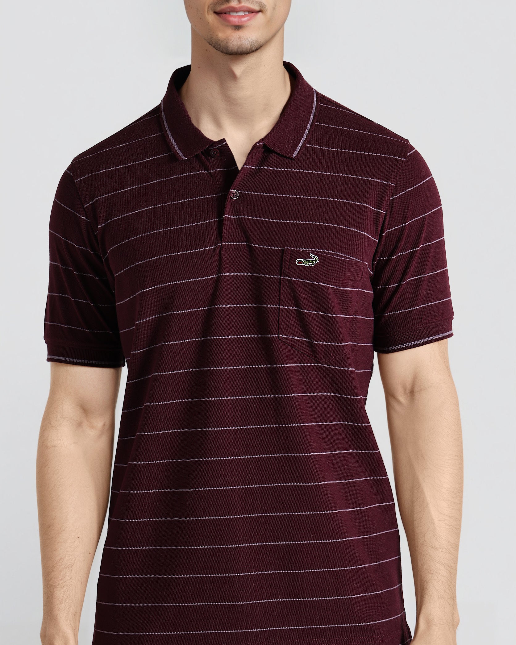 Man wearing a maroon striped polo shirt on a light gray background