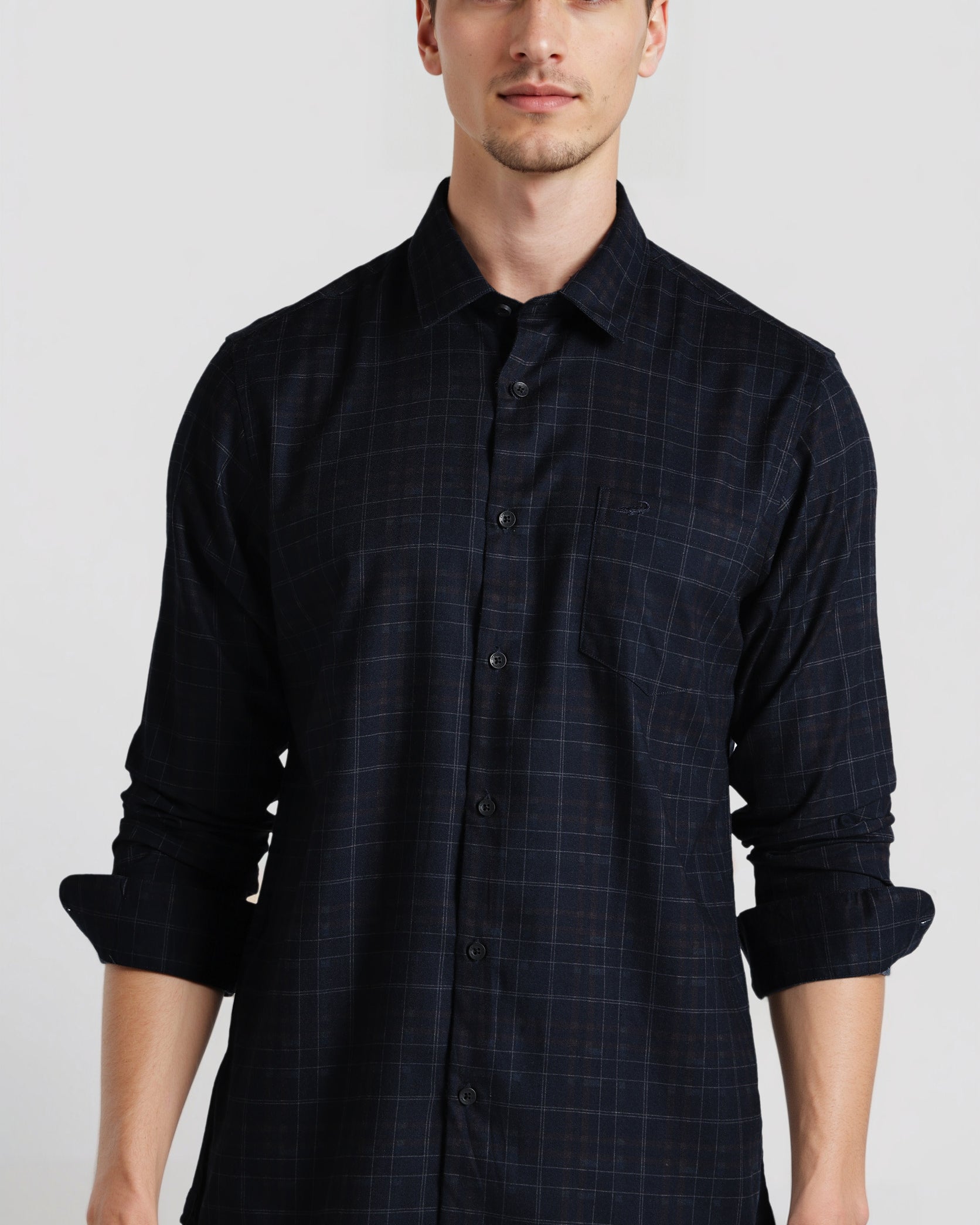 Man wearing a dark blue checkered shirt against a plain background