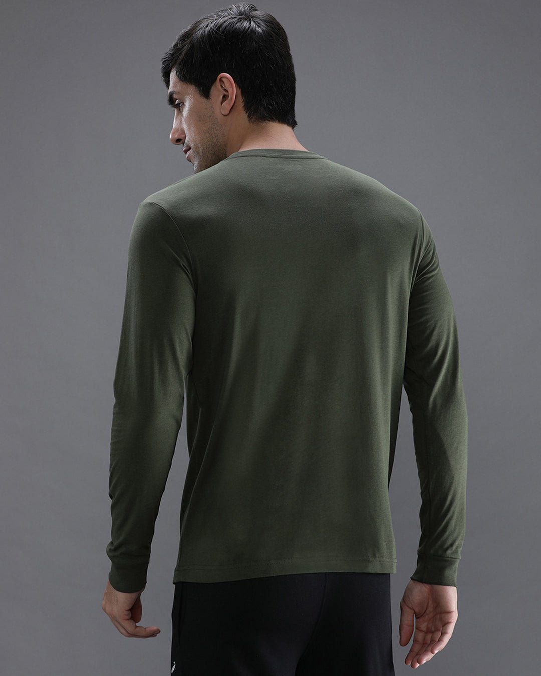 Man wearing a green solid green sport fit t shirt with casual styling on a gray background