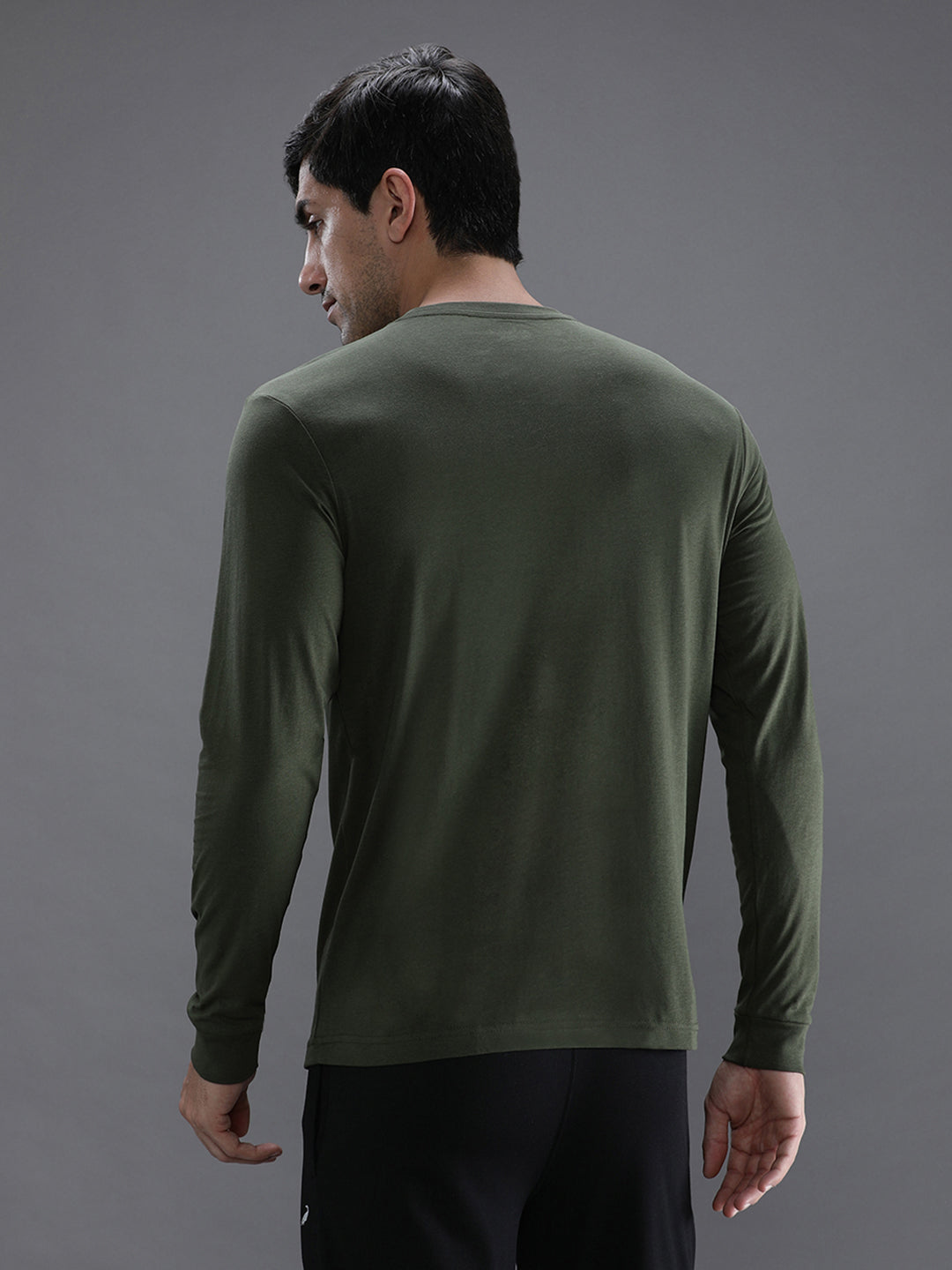 Man wearing a green solid green sport fit t shirt with casual styling on a gray background