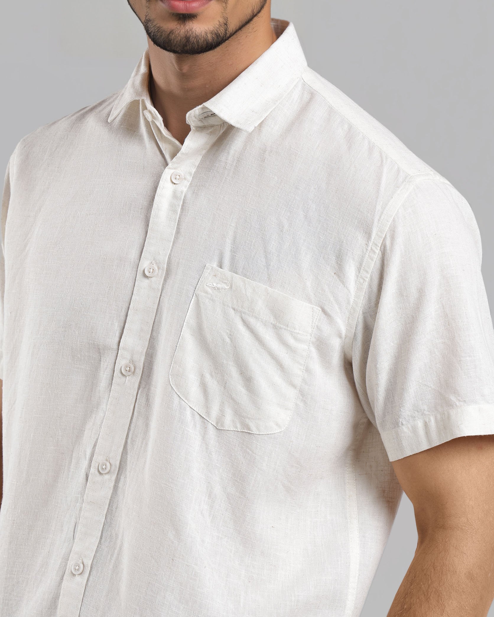 Man wearing a white short-sleeve shirt against a gray background
