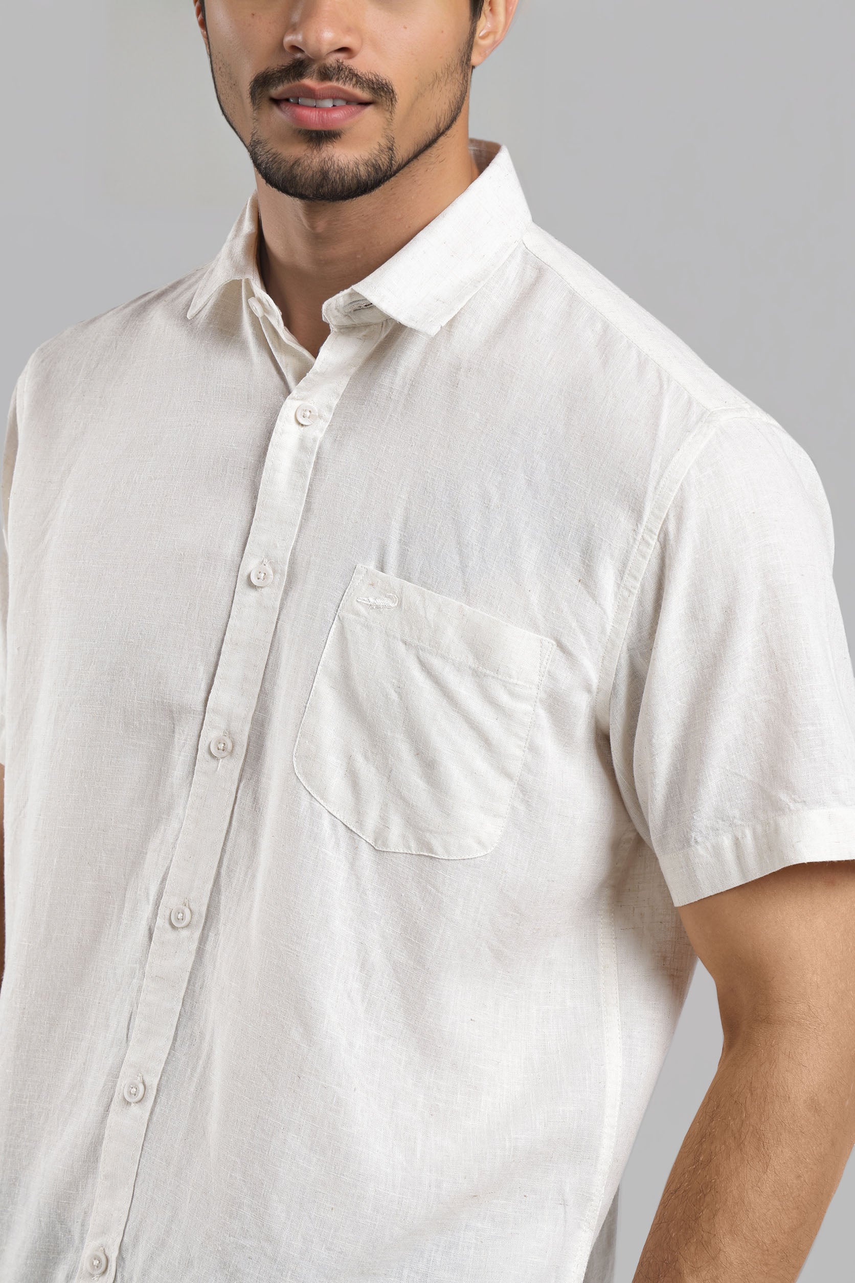 Man wearing a white short-sleeve shirt against a gray background
