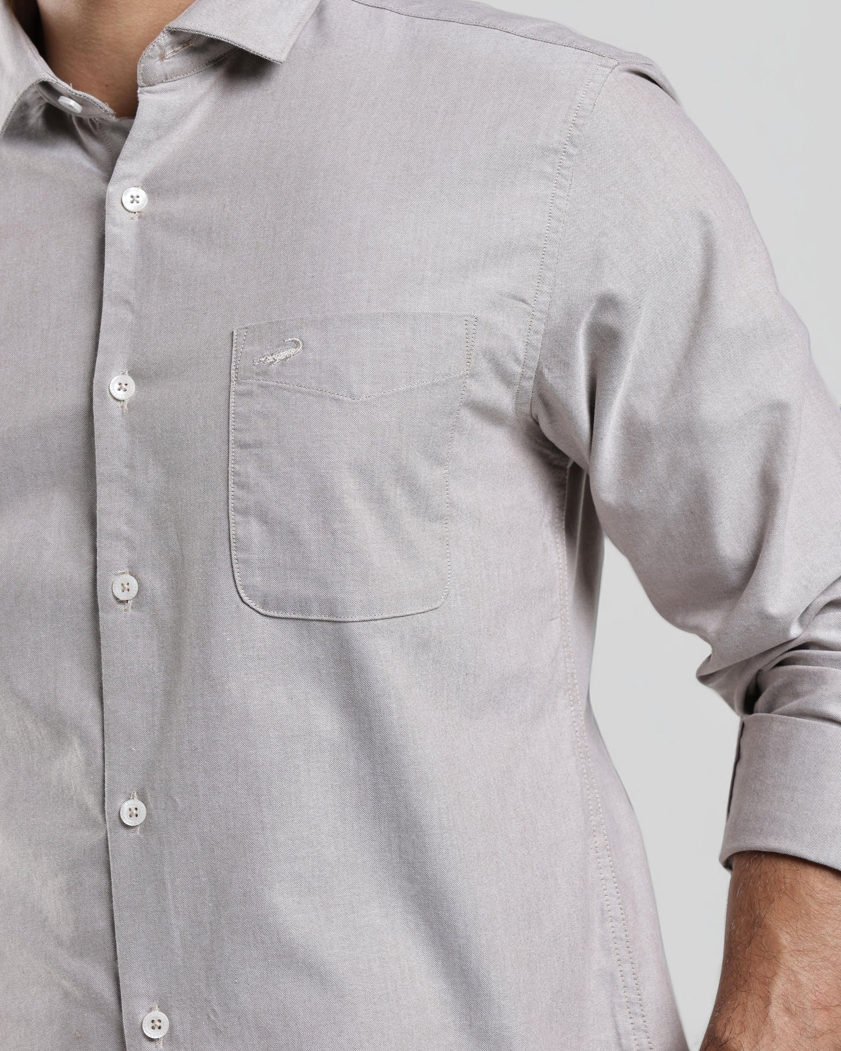 Close-up of a gray button-up shirt worn by a person on a light gray background