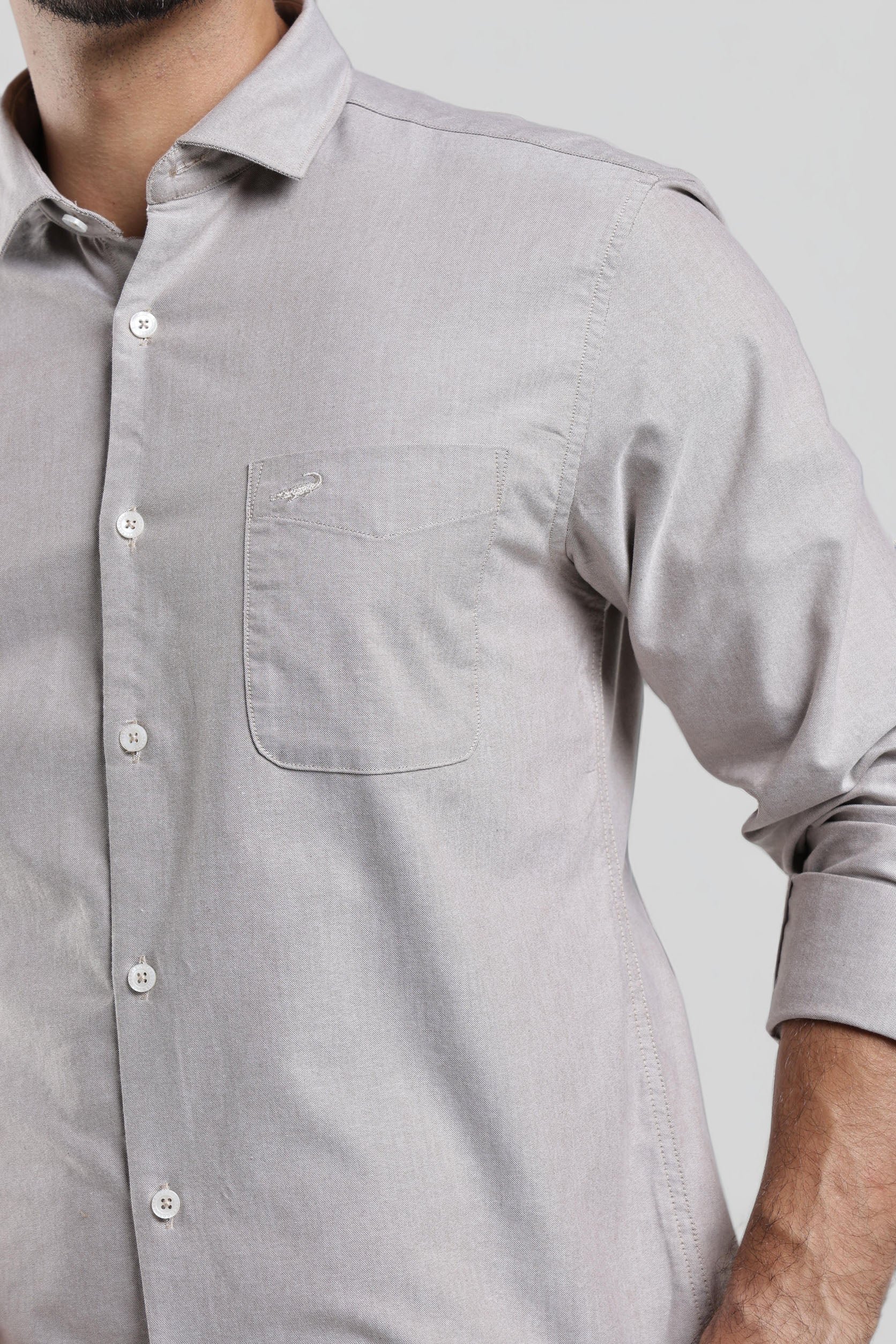 Close-up of a gray button-up shirt worn by a person on a light gray background