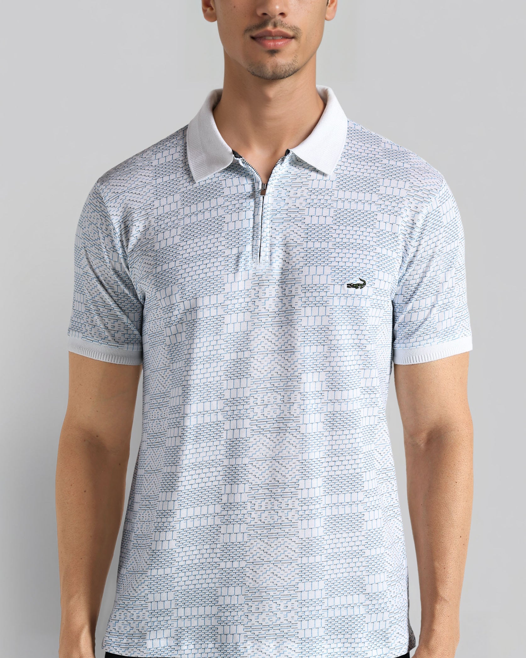 Man wearing a light blue patterned polo shirt on a gray background