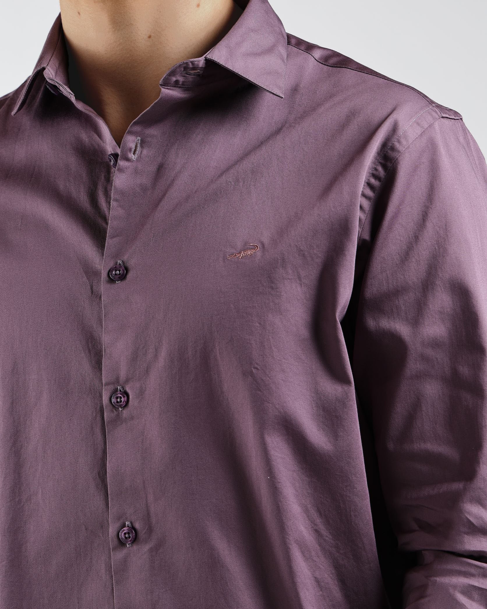Close-up of a person wearing a purple shirt with a brand logo on a white background