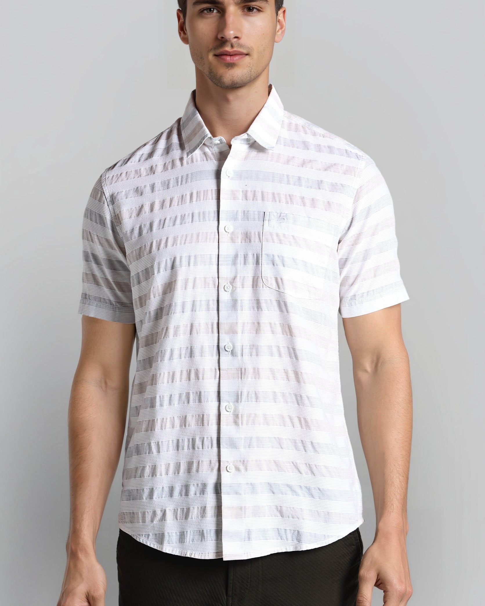 Man wearing a white patterned shirt against a gray background