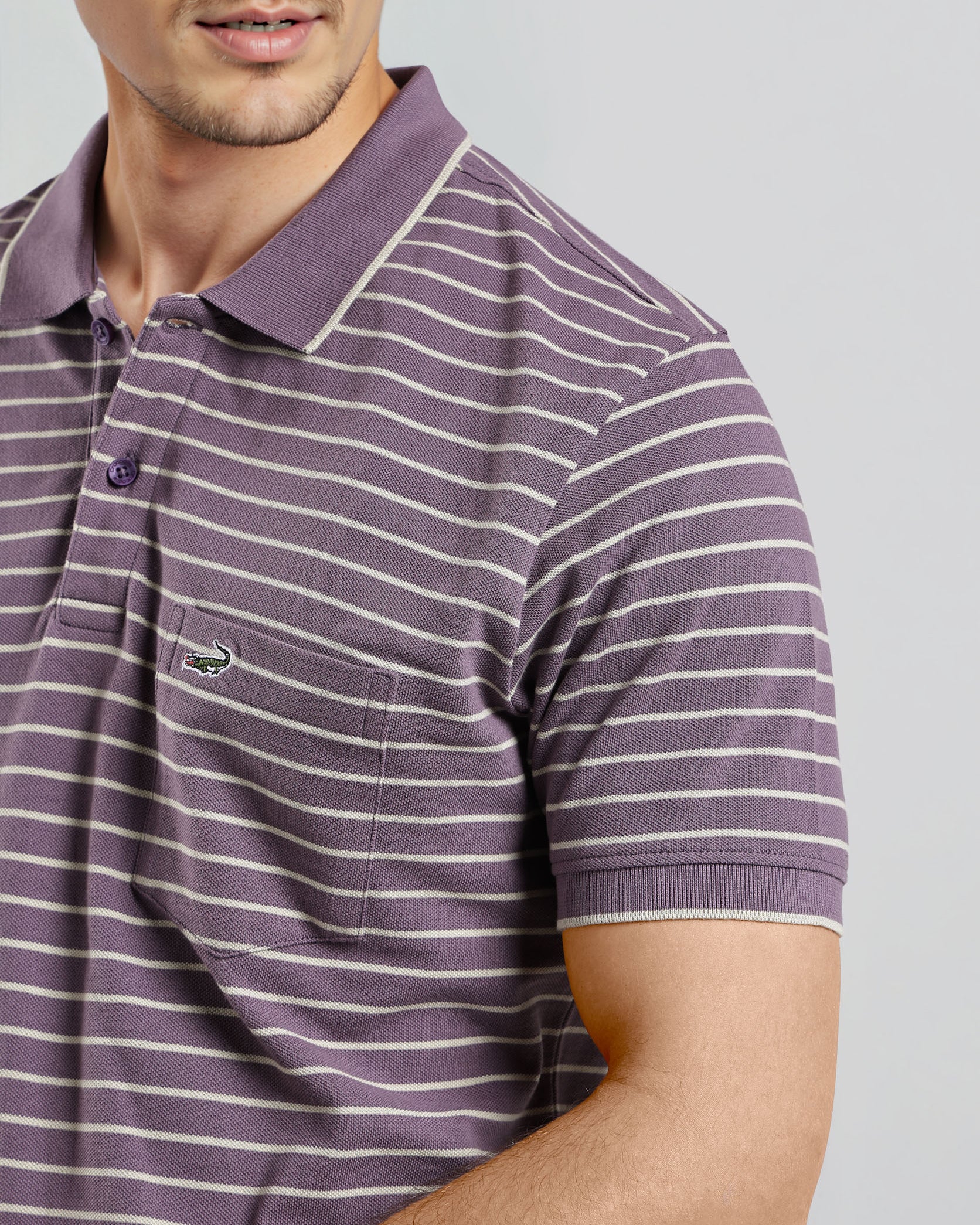 Man wearing a purple and white striped polo shirt on a gray background
