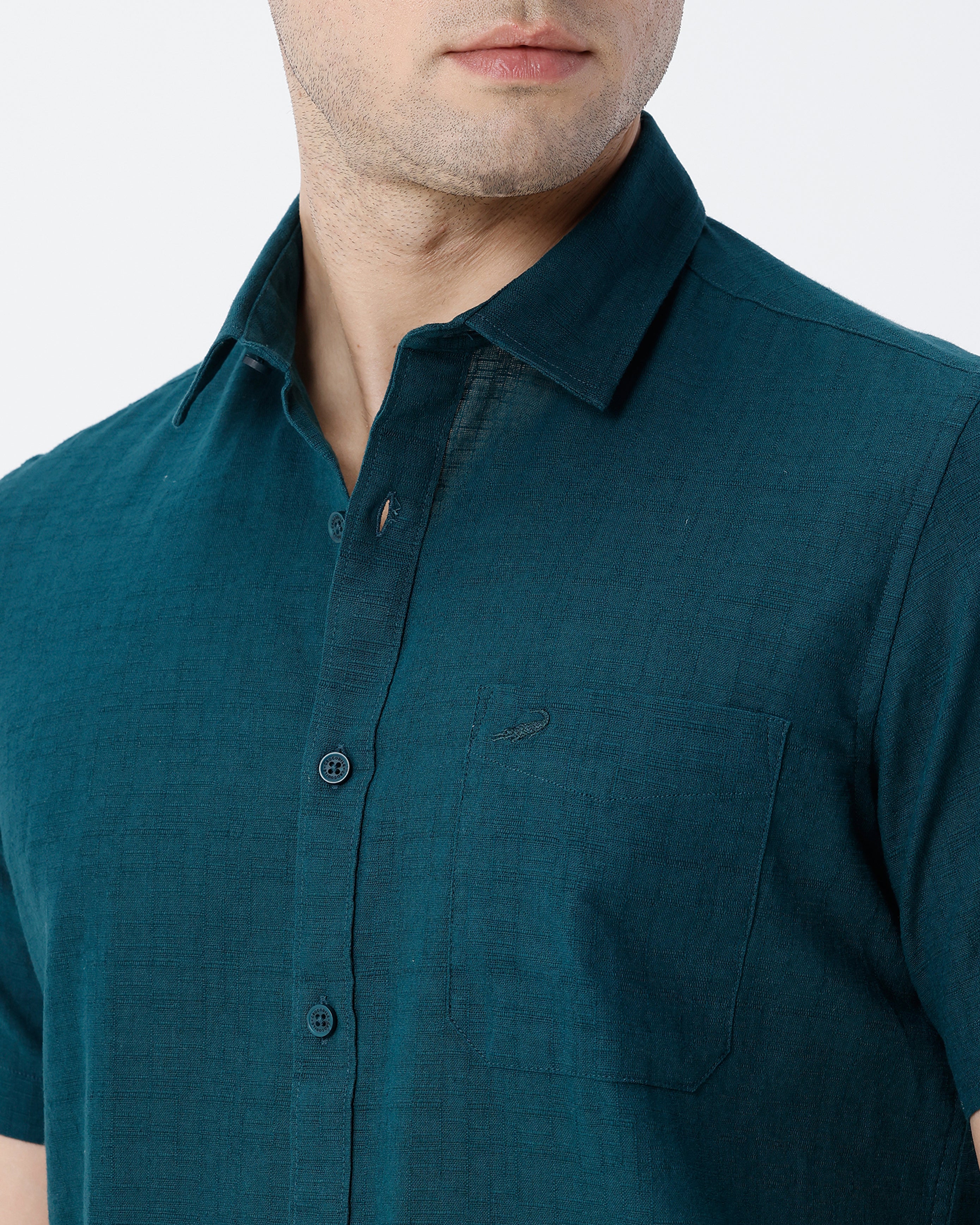 Man wearing a green pure cotton textured shirt green with casual styling on a gray background