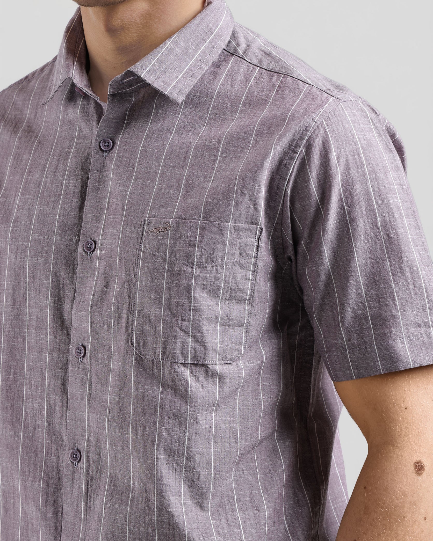 Man wearing a short-sleeve, button-up shirt with a subtle pattern against a neutral background