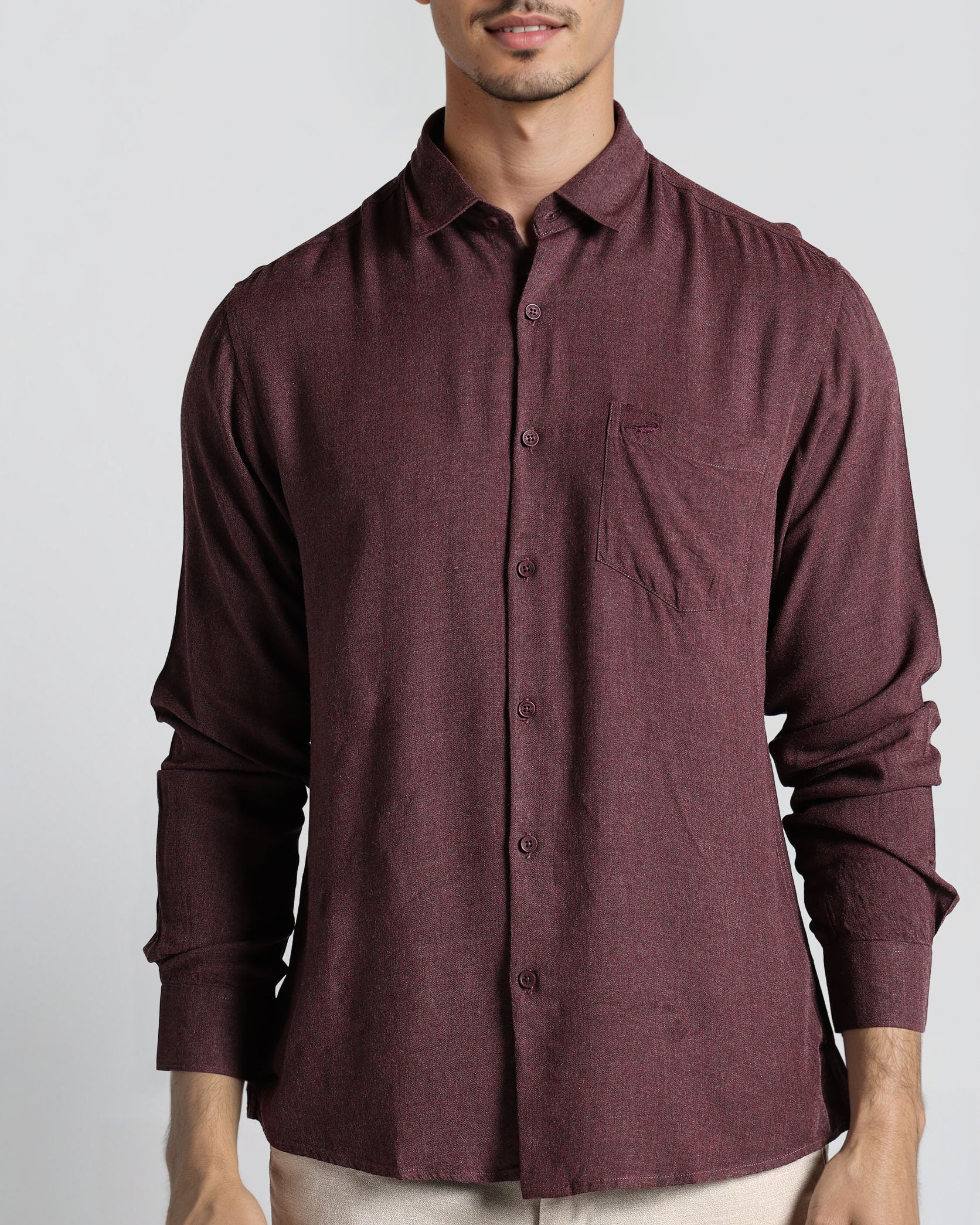 Man wearing a maroon button-up shirt against a plain background