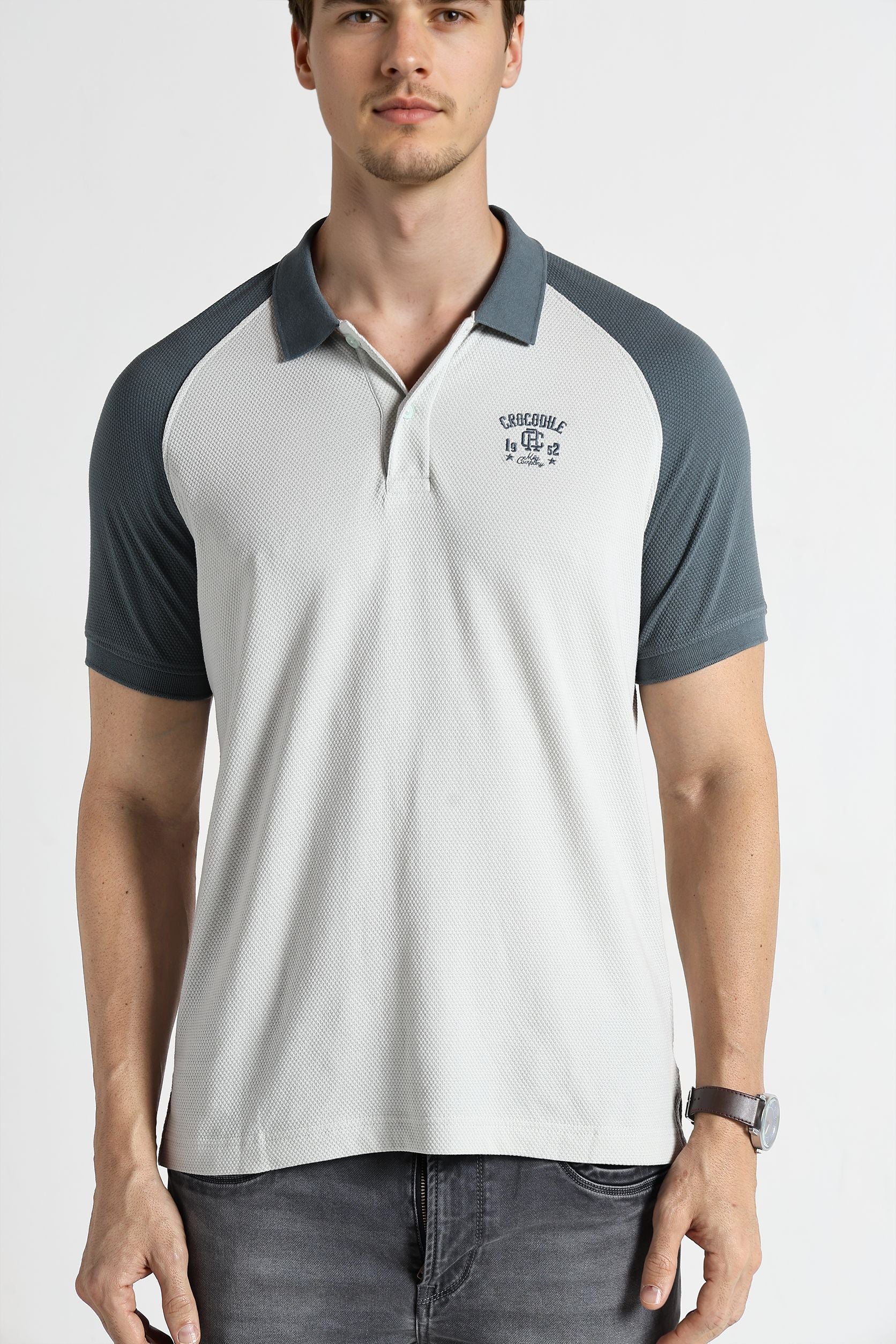 Man wearing a white and navy polo shirt with a visible brand logo on a white background