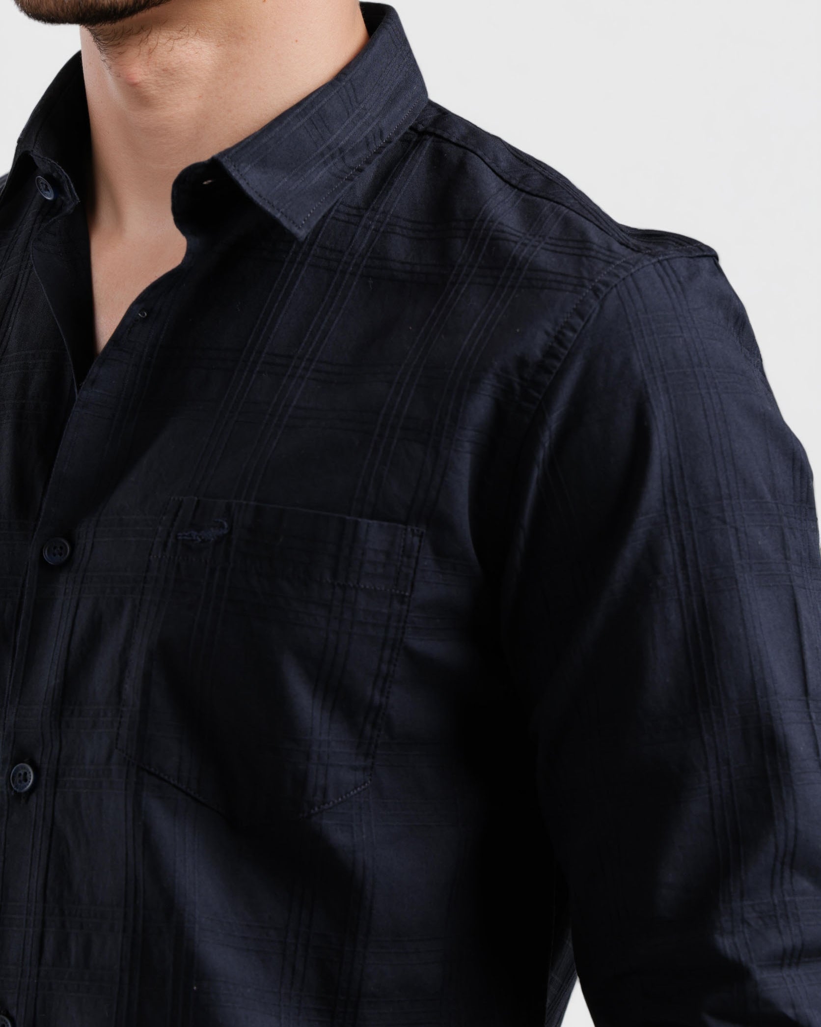 Close-up of a person wearing a dark blue shirt against a light background
