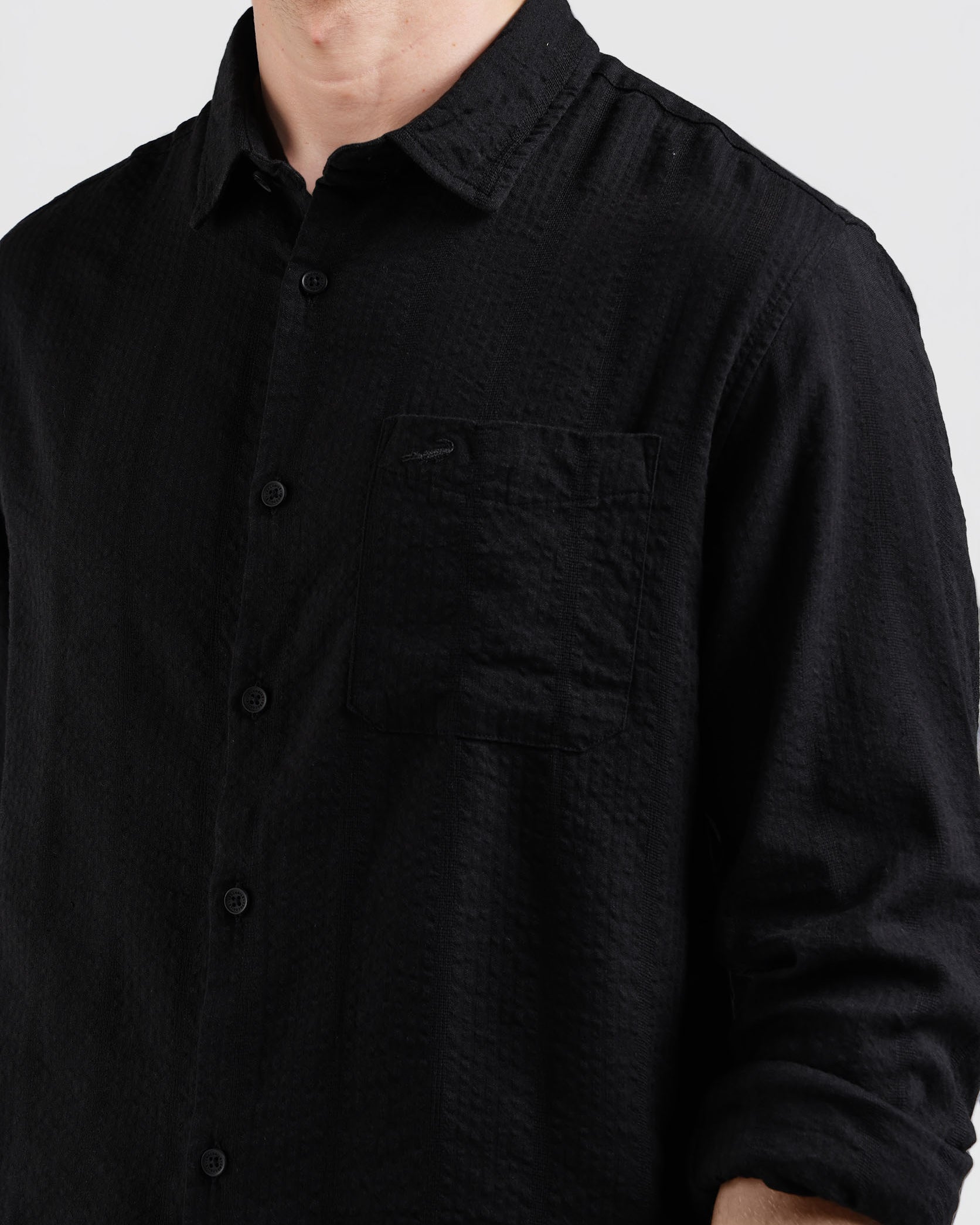 Black button-up shirt worn by a person on a plain background